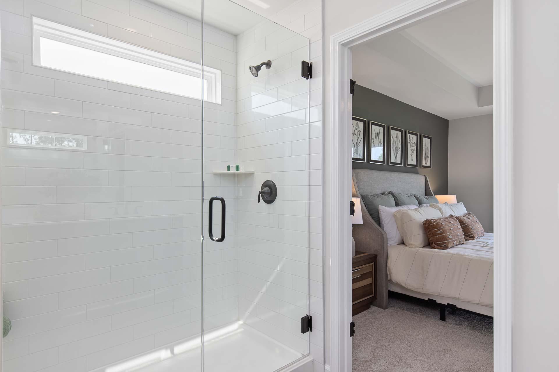 Modern master bathroom with frameless glass shower and adjacent bedroom at Sierra Heights in Clayton, North Carolina
