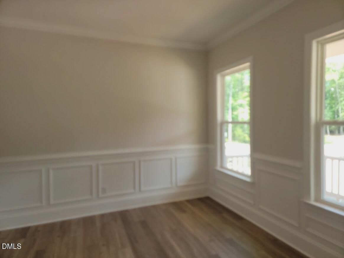 Bright dining room with wainscoting, hardwood floors, and large windows in Davidson Homes Magnolia II B, Wake Forest, NC