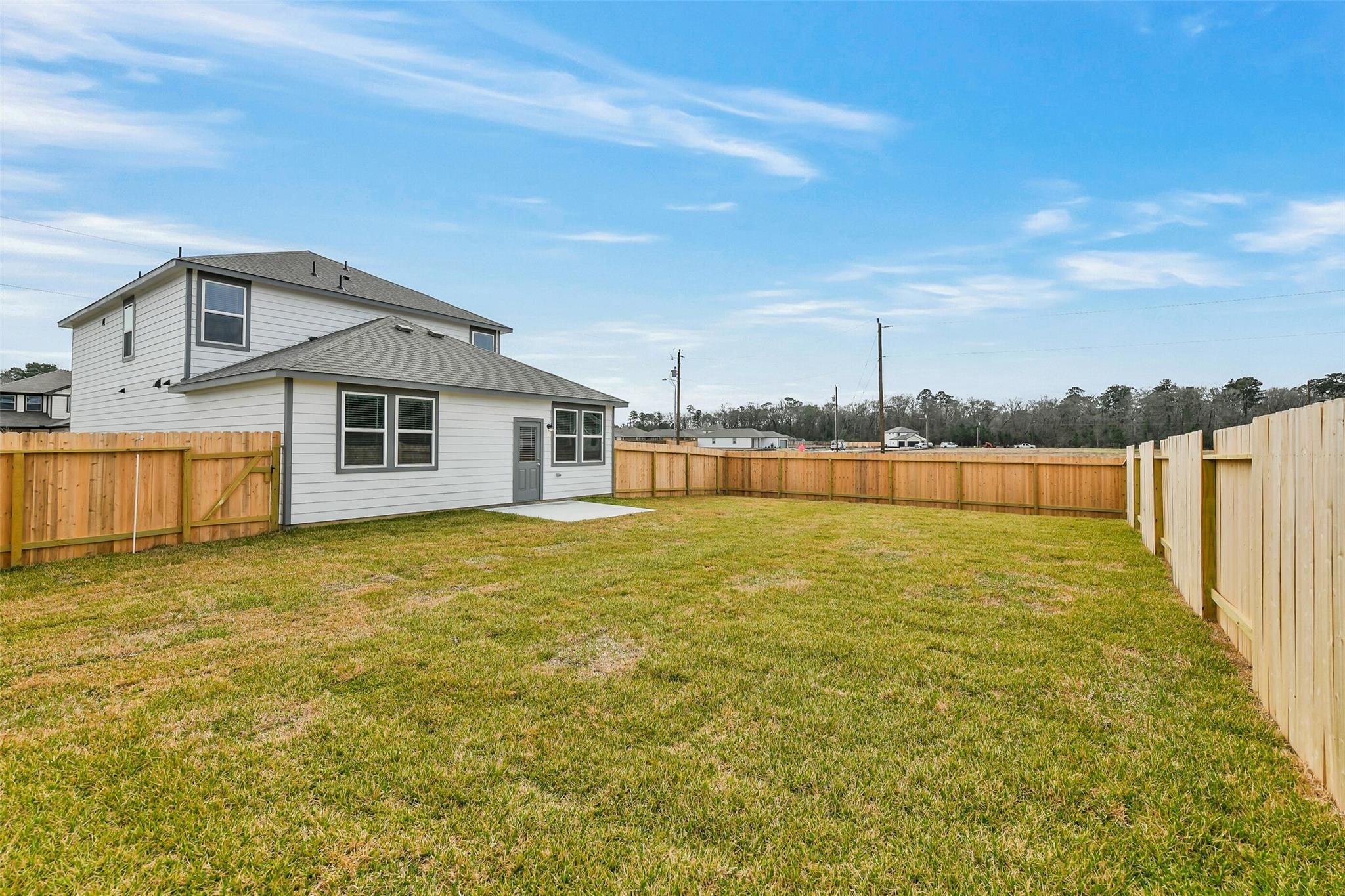 Rear view of The Brazos E two-story home with fenced grassy backyard in Liberty Estates, Cleveland, Texas