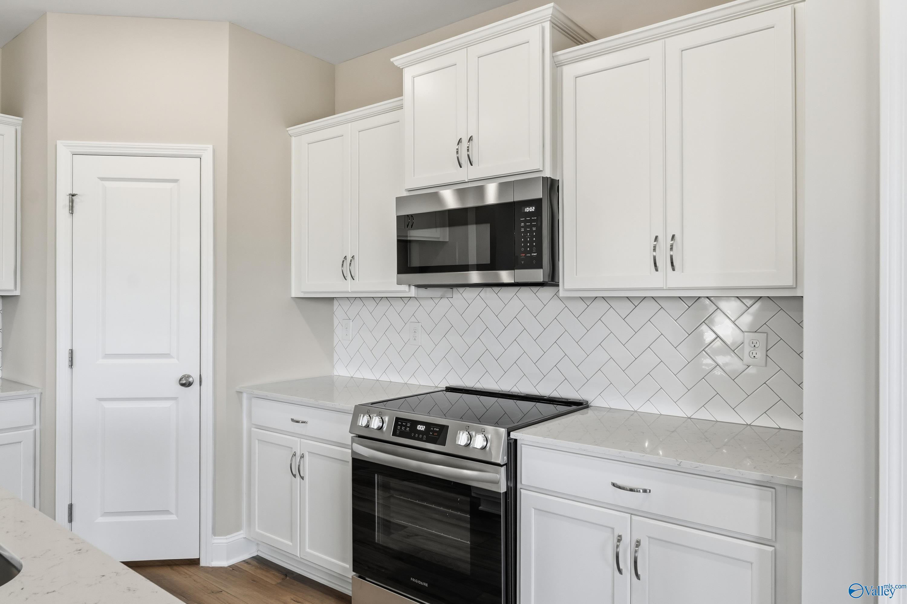 Modern kitchen featuring white shaker cabinets, stainless steel range and microwave, subway tile backsplash in Davidson Homes The Franklin C, New Market, AL
