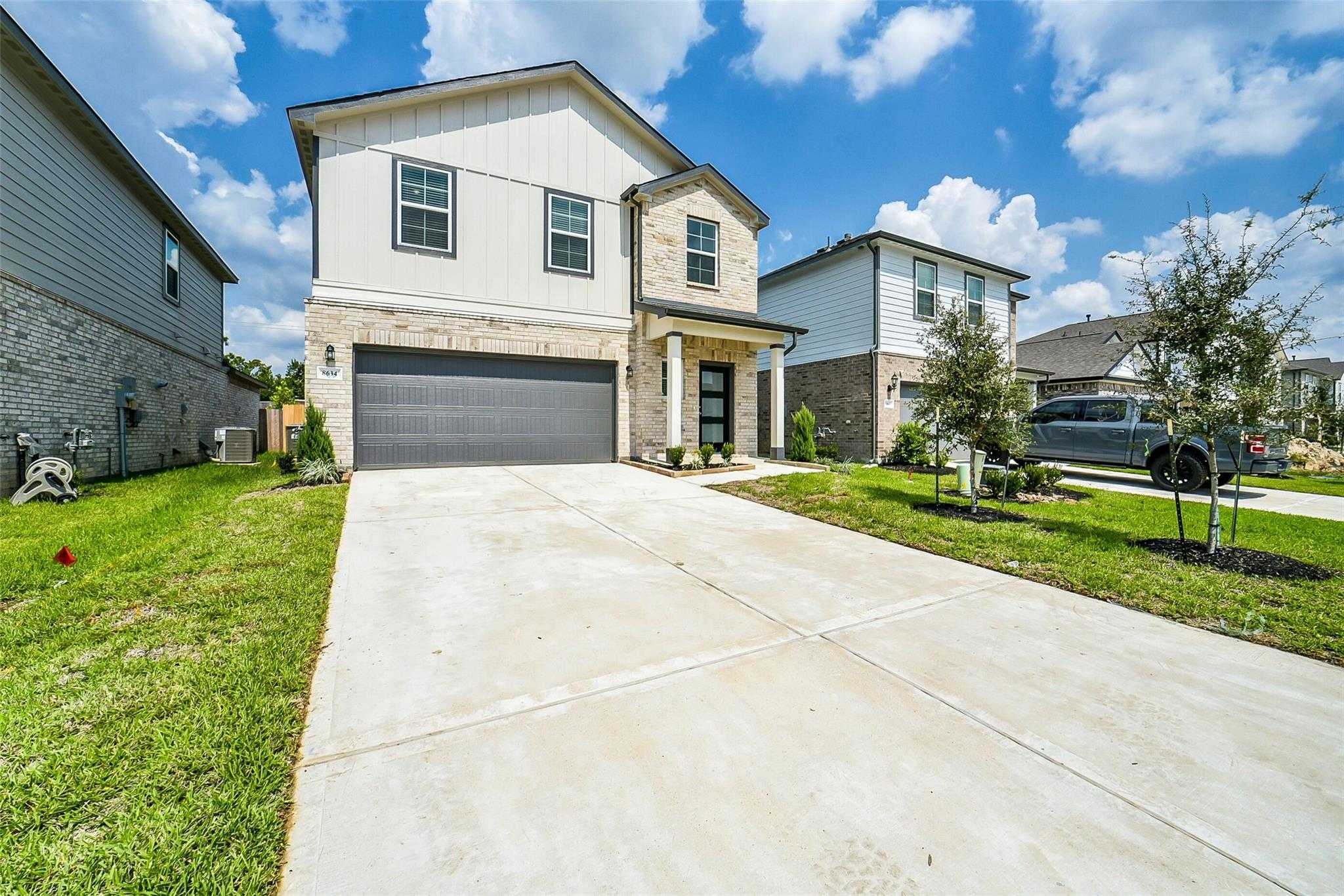 Modern 2-story Davidson Homes Trinity F with stone accents, 2-car garage, driveway, and lush landscaping in Lakes at Black Oak, Magnolia, Texas