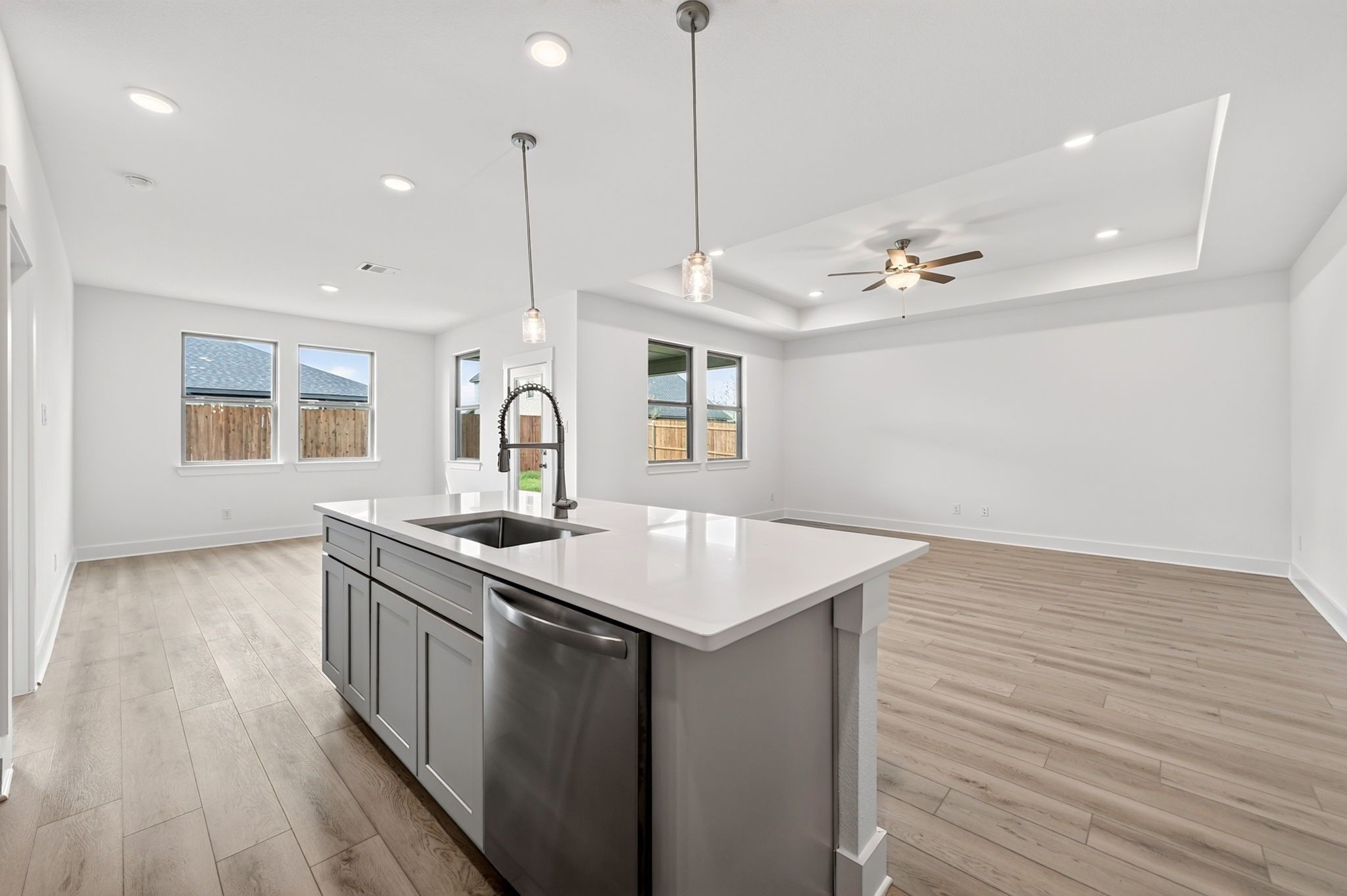 Open-concept kitchen with gray island, white quartz countertops, and luxury vinyl plank flooring in Davidson Homes The Holly F, Josephine, TX