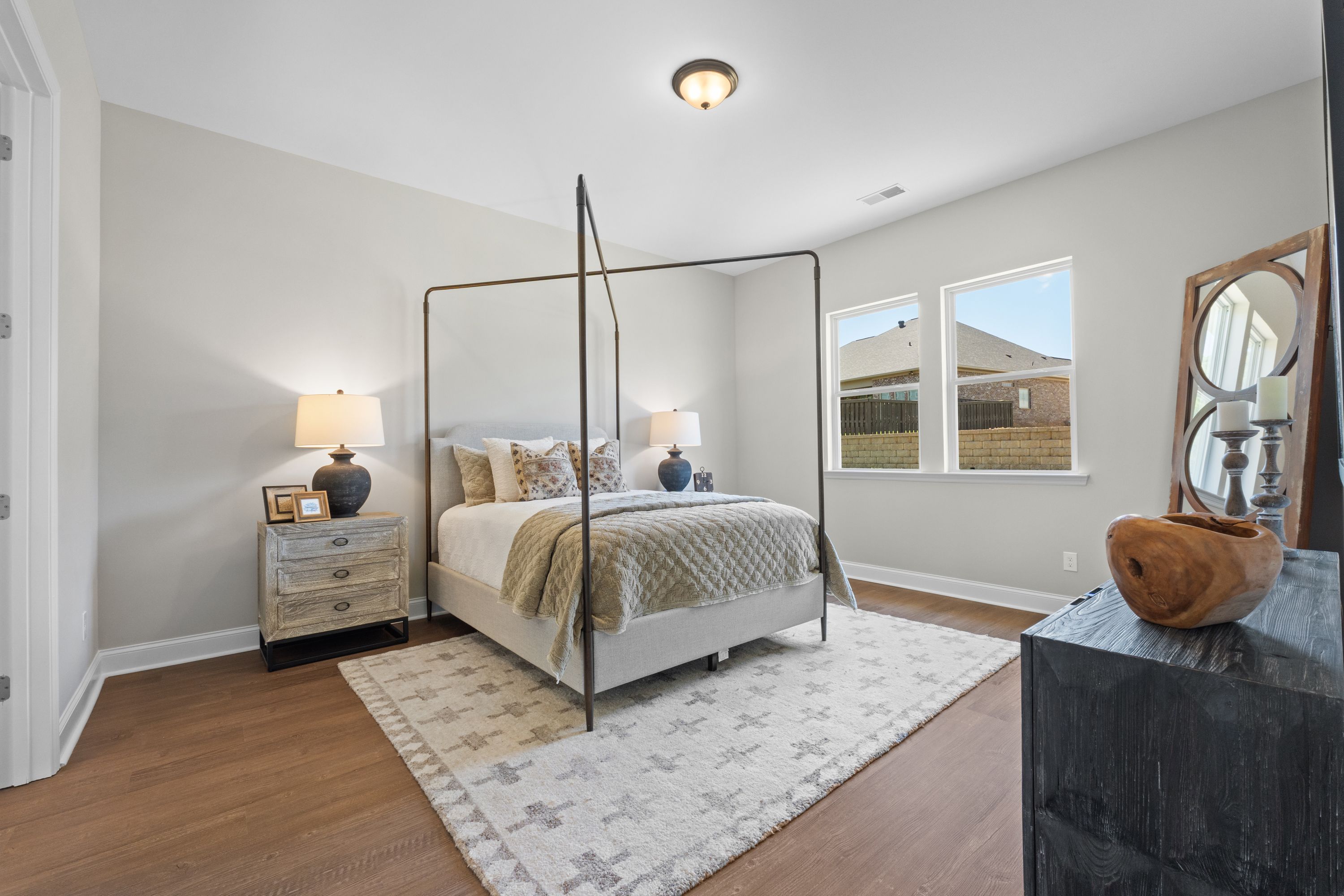 Spacious master bedroom in The Haven D with canopy bed, neutral walls, hardwood floors, and large windows