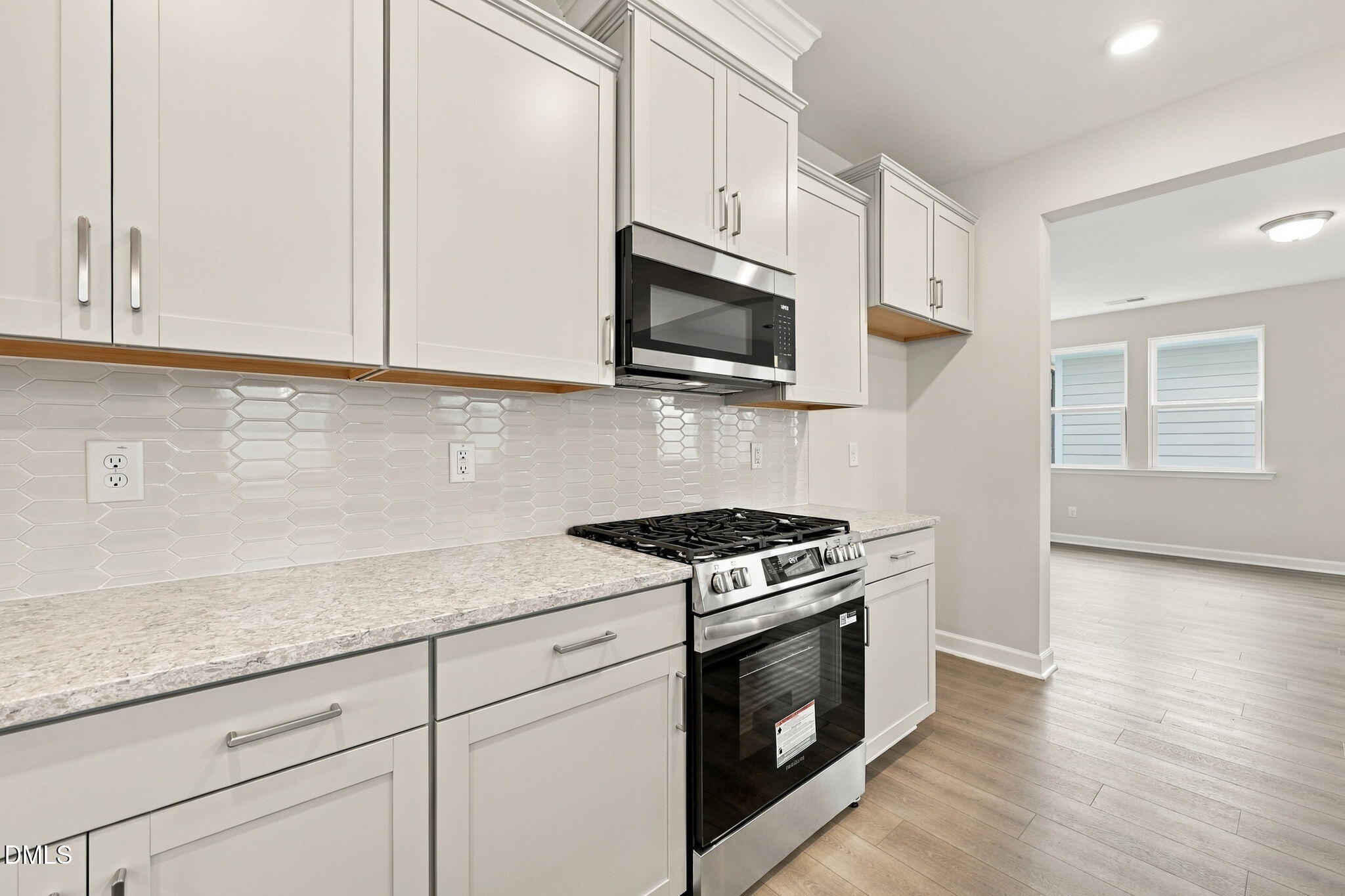 Modern kitchen with white shaker cabinets, stainless gas range, microwave, and hex tile backsplash in Davidson Homes' Alexander B plan, Knightdale NC