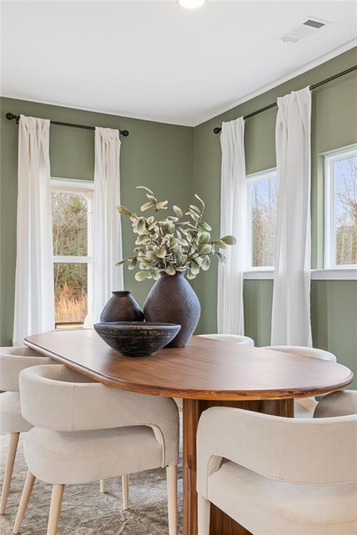 Modern dining room with oval wood table and cream chairs in The Rabun B floor plan at The Bluffs, Canton, Georgia.