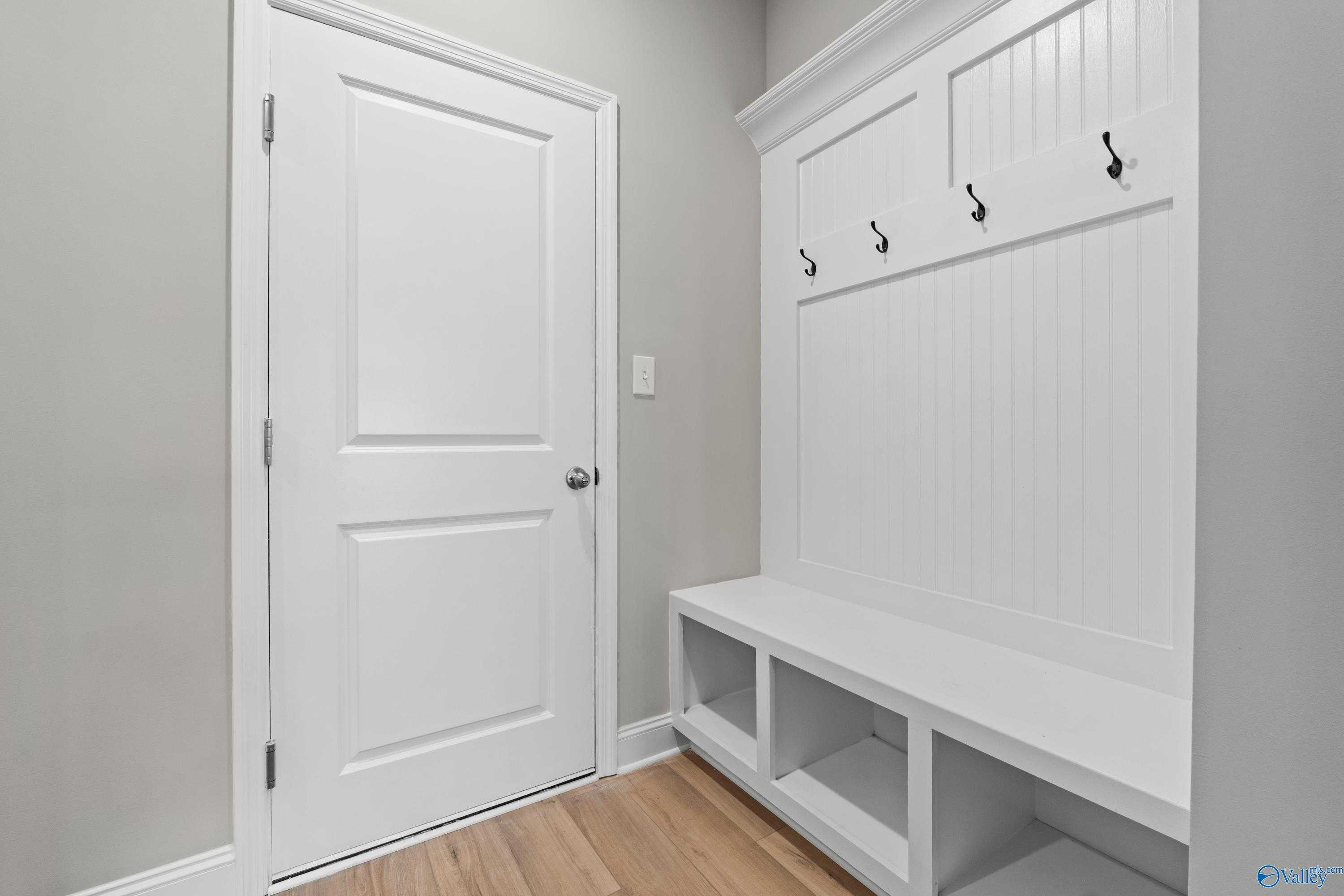 Spacious mudroom with white shiplap cabinet, coat hooks, and built-in bench in Davidson Homes The Finleigh, Meridianville, Alabama