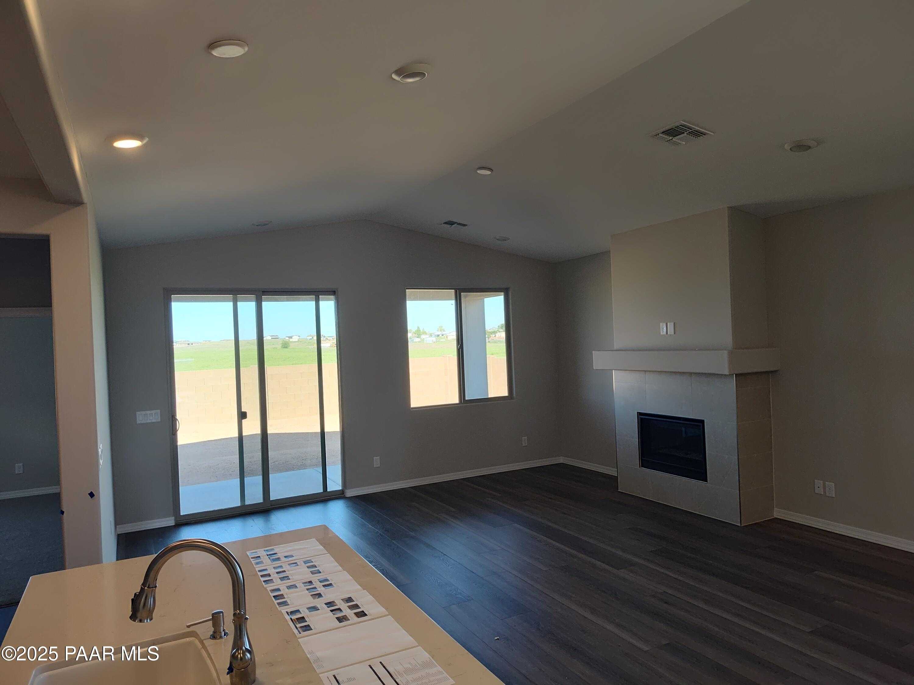 Open-concept living area with gas fireplace, kitchen island sink, and sliding doors to desert view in Davidson Homes The Frontier A, Prescott Valley