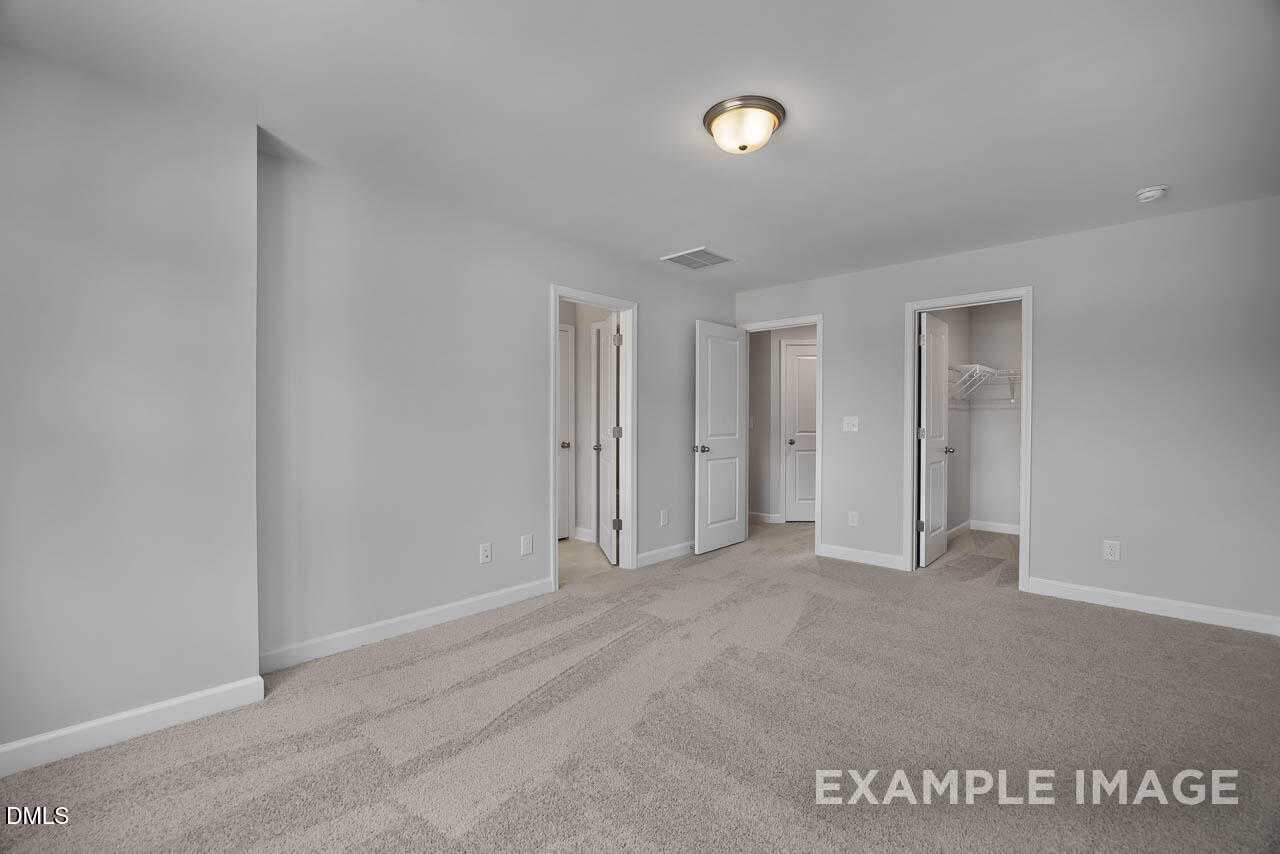Bright upstairs hallway with light gray walls, beige carpet, and doors to bedrooms and closet in Davidson Homes The Warren Interior, Fuquay-Varina, NC
