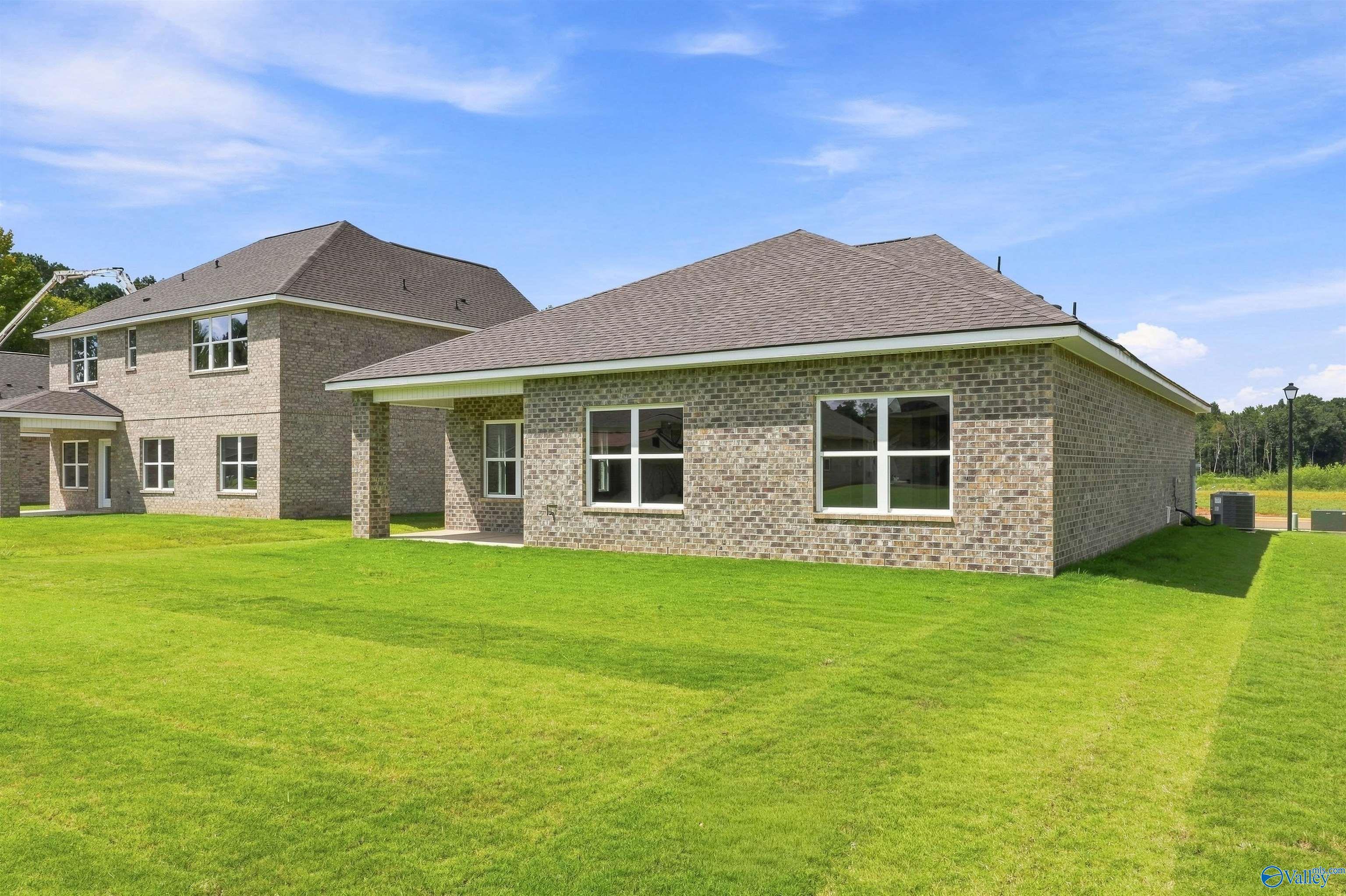 Rear view of brick single-story Franklin C home by Davidson Homes with covered patio and large backyard in Wood Trail, Toney, Alabama