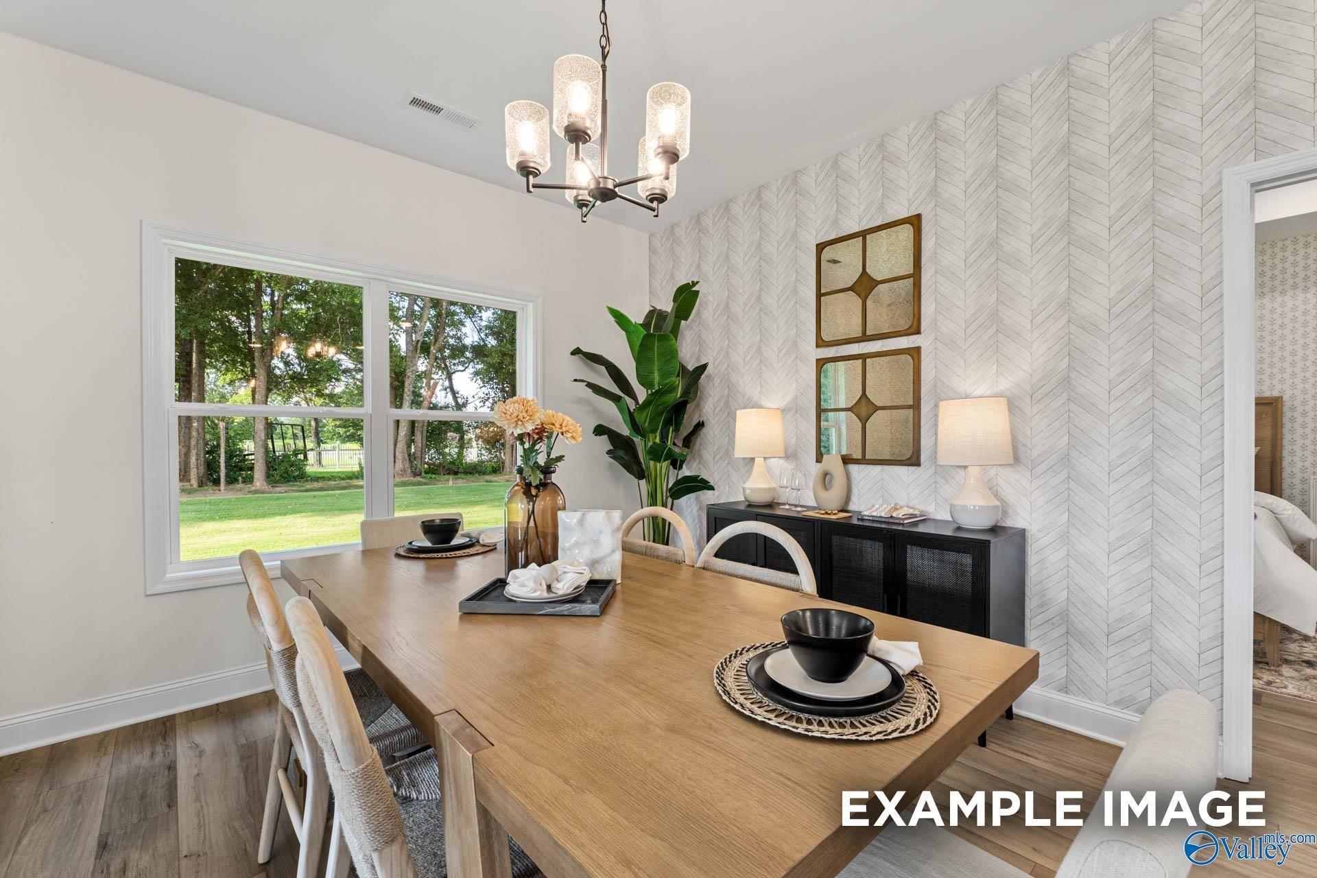 Elegant dining room with patterned wallpaper, large windows to lush yard, wooden table, and chandelier in Davidson Homes The Franklin, Huntsville, AL