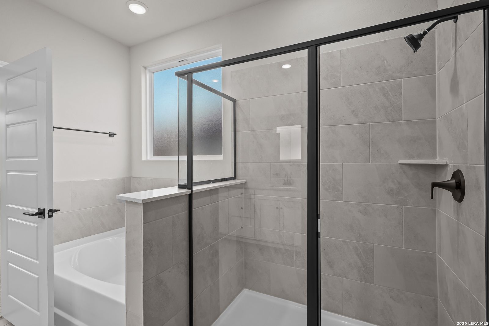 Modern bathroom with glass walk-in shower, matte black fixtures, and garden tub in Davidson Homes The Sequoia C, San Antonio