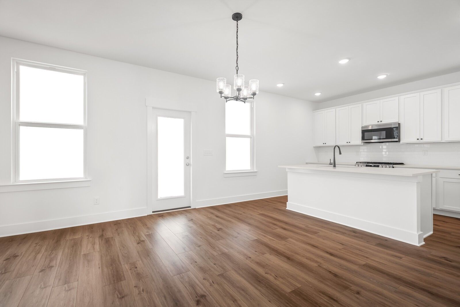 Bright open-concept kitchen with white cabinets, granite island, stainless appliances, chandelier in The Logan C, Gallatin TN