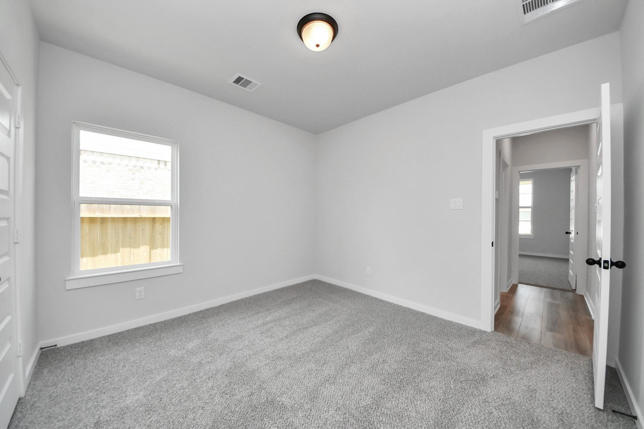 Bright secondary bedroom with plush carpet in The Everett C floor plan by Davidson Homes in River Ranch Meadows, Dayton, TX.