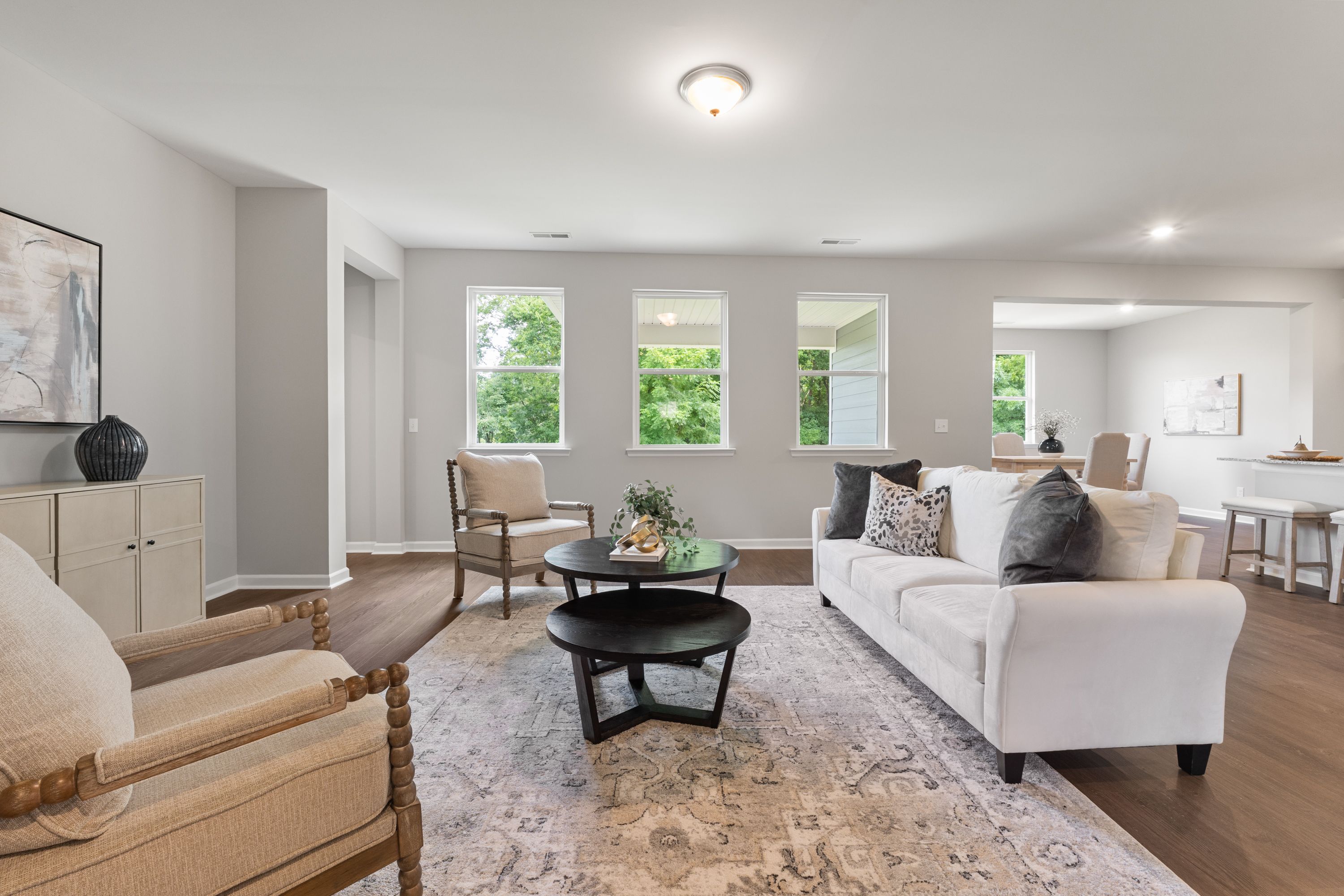 Spacious living room in The Avalon E with white sectional sofa, black coffee table, large windows, neutral walls, hardwood floors