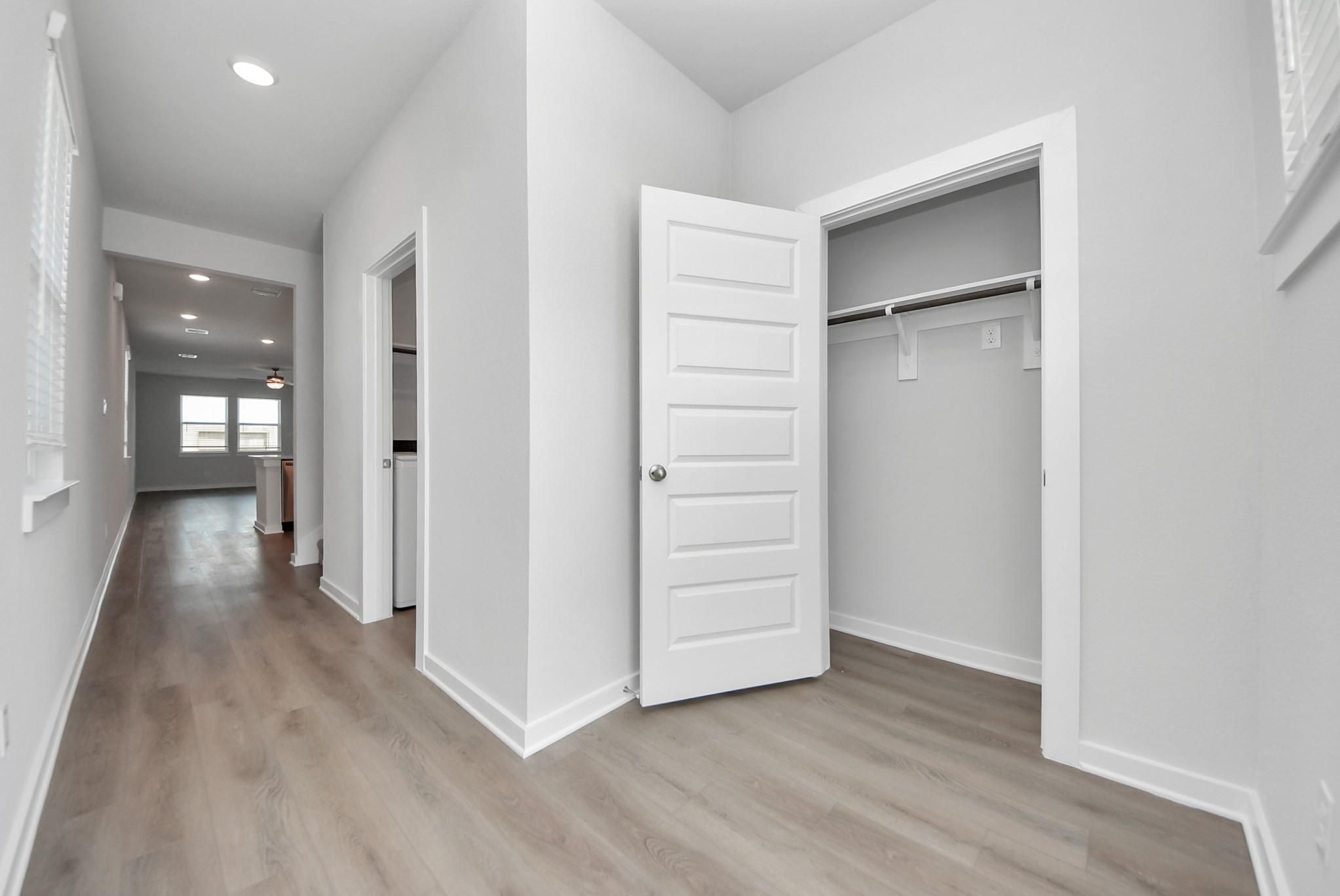 Bright hallway with wood-look flooring and walk-in closet in Davidson Homes The San Marcos E, Emberly, Beasley, Texas