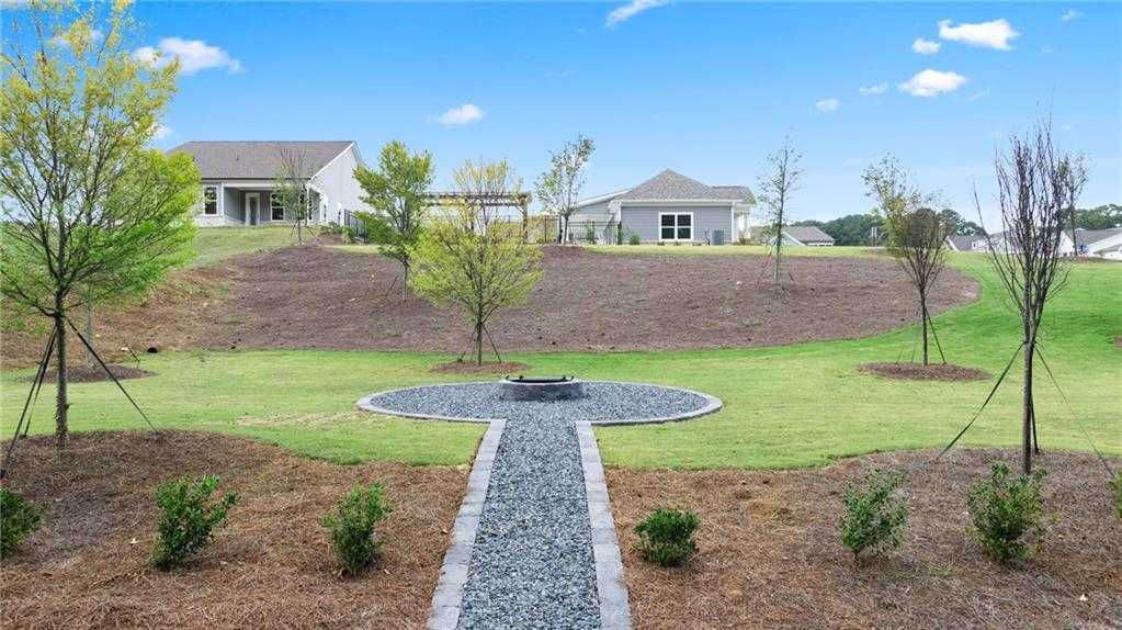 Scenic landscaped green space with circular gravel fire pit, stone path, trees, shrubs, and Davidson Homes in Kelly Preserve, Loganville, Georgia