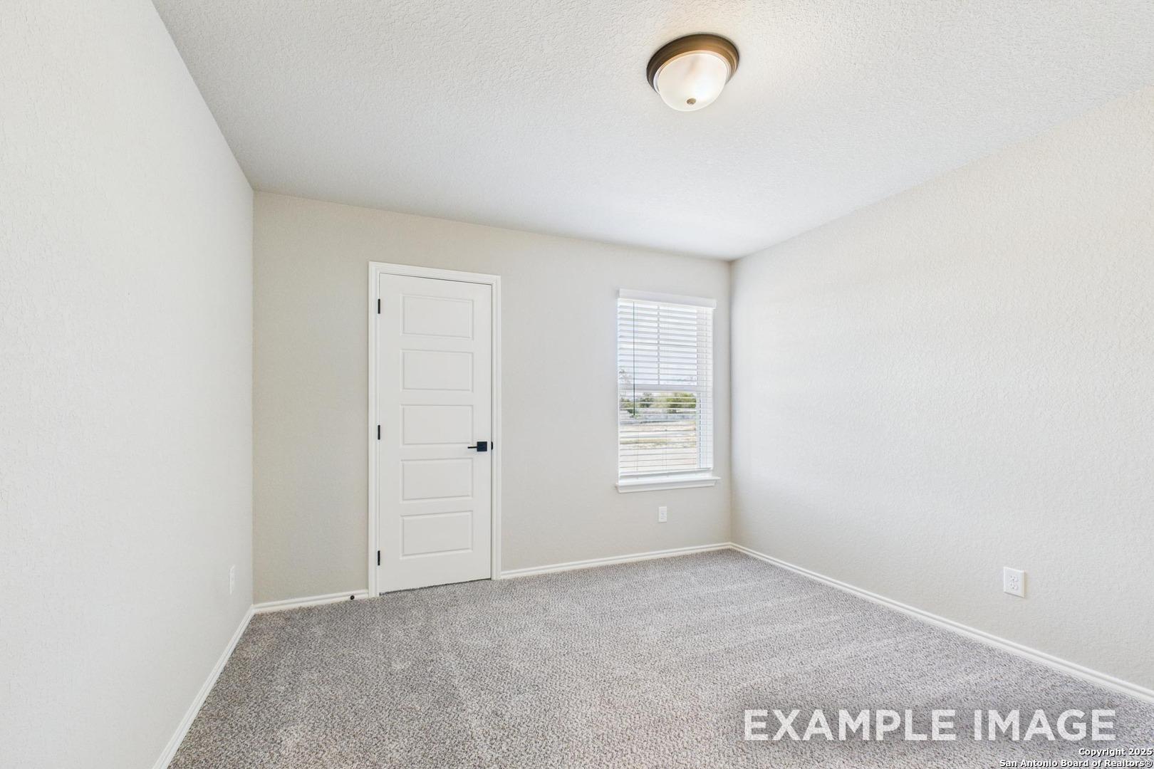 Spacious empty bedroom with gray carpet, beige walls, window blinds and ceiling light in Davidson Homes The Charlotte B, San Antonio, Texas