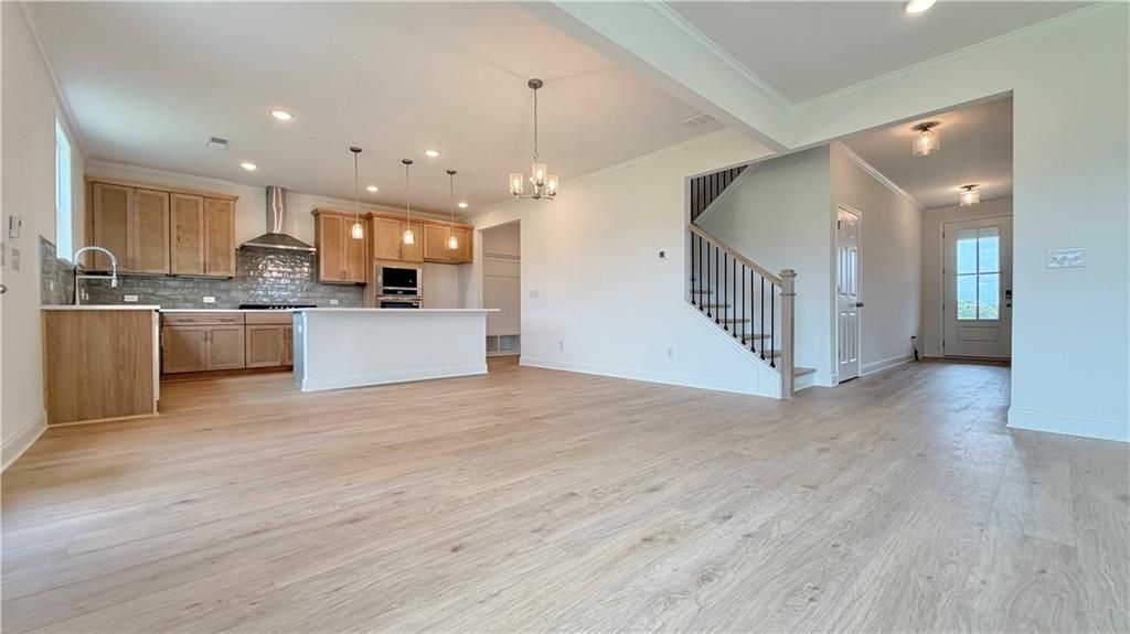 Open-concept kitchen and living area with hardwood floors in The Hickory C floor plan by Davidson Homes in Hoschton, GA.
