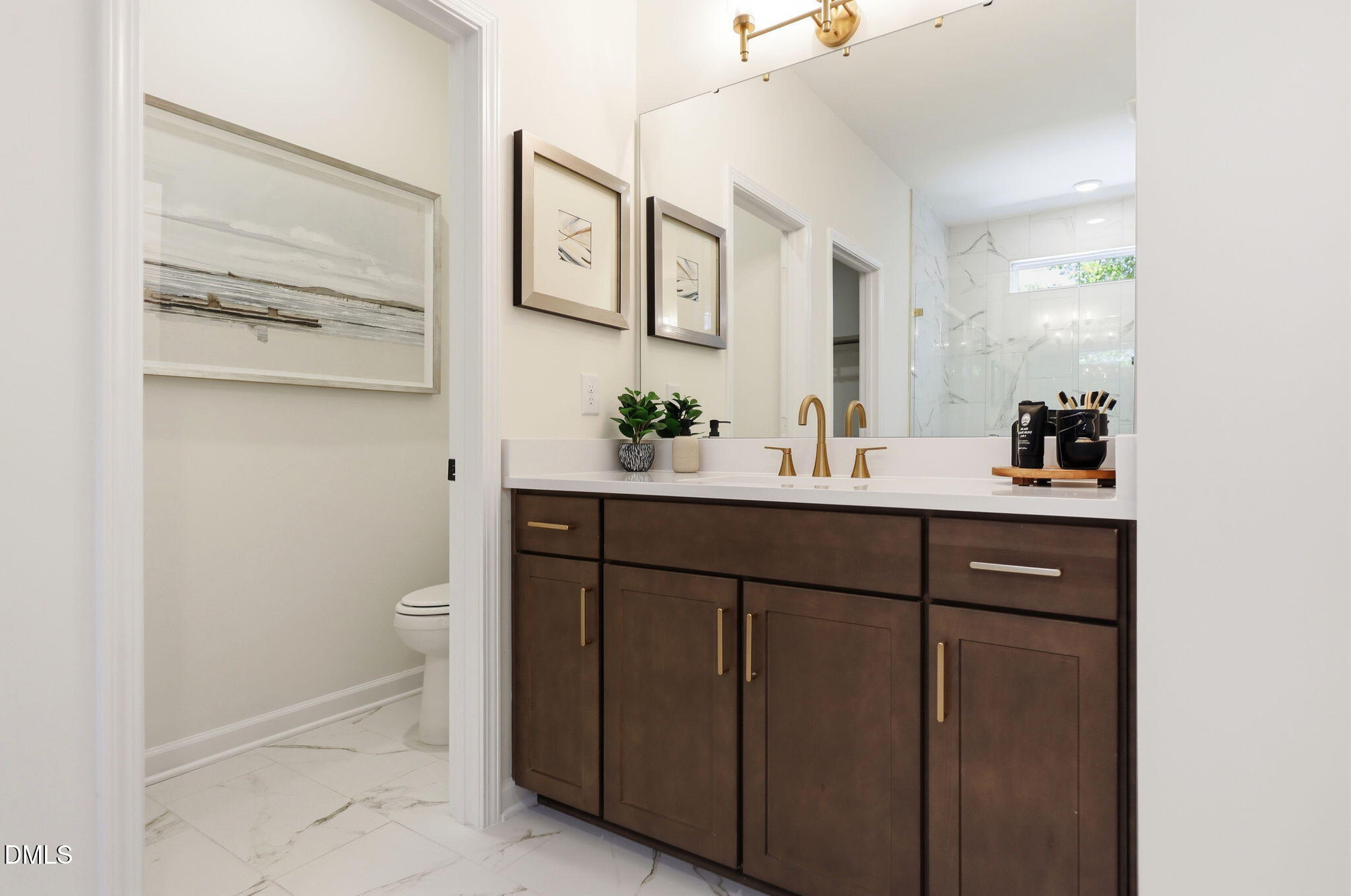 Modern bathroom with dark wood vanity, gold fixtures, and marble tile in The Aspen B home at Wendell Ridge, North Carolina.