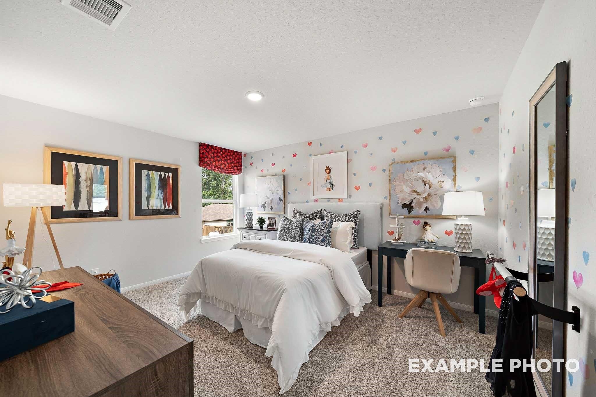 Charming girl's bedroom with heart decals, twin bed, wooden desk, and mirrored wall in 5-bedroom Davidson Homes San Marcos E, Conroe, TX