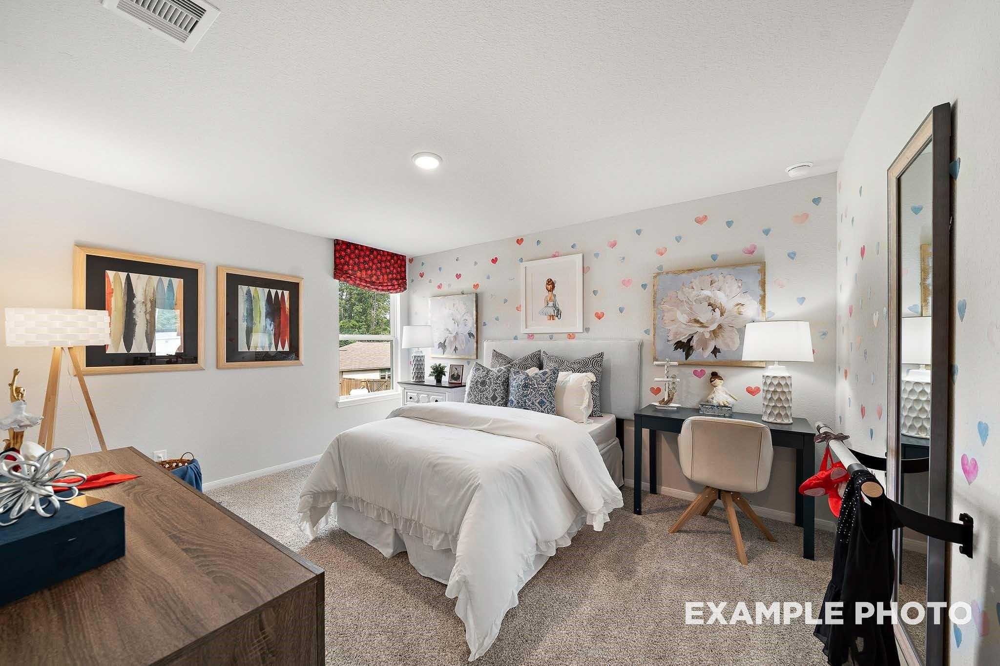 Charming girl's bedroom with heart decals, twin bed, wooden desk, and mirrored wall in 5-bedroom Davidson Homes San Marcos E, Conroe, TX