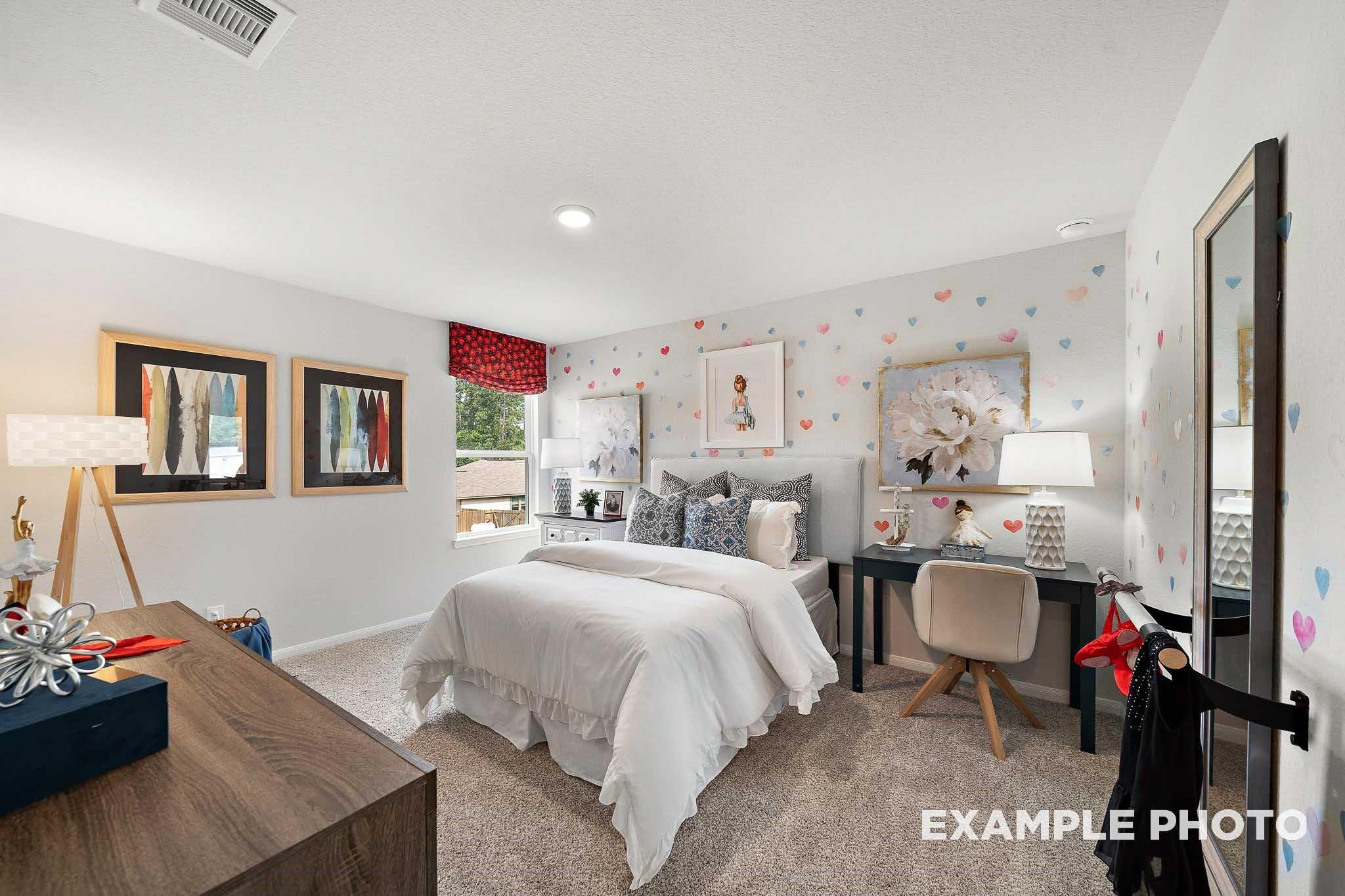 Charming girl's bedroom with heart decals, twin bed, wooden desk, and mirrored wall in 5-bedroom Davidson Homes San Marcos E, Conroe, TX