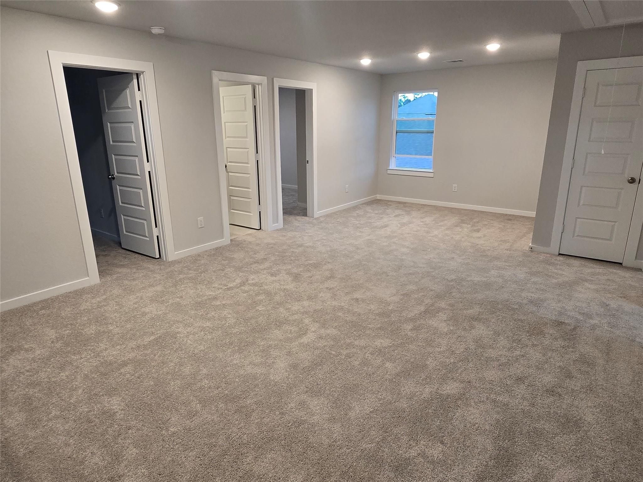 Spacious upstairs hallway with beige carpet, light gray walls, open bedroom doors, and side window in 5-bedroom Davidson Homes The Brazos E, Cleveland, Texas