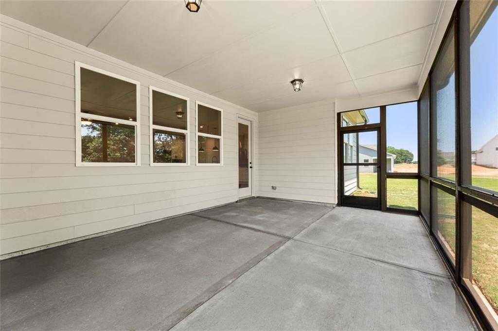 Spacious screened porch with concrete floor, large windows, and white siding in Davidson Homes The Harrison G, Hoschton, GA