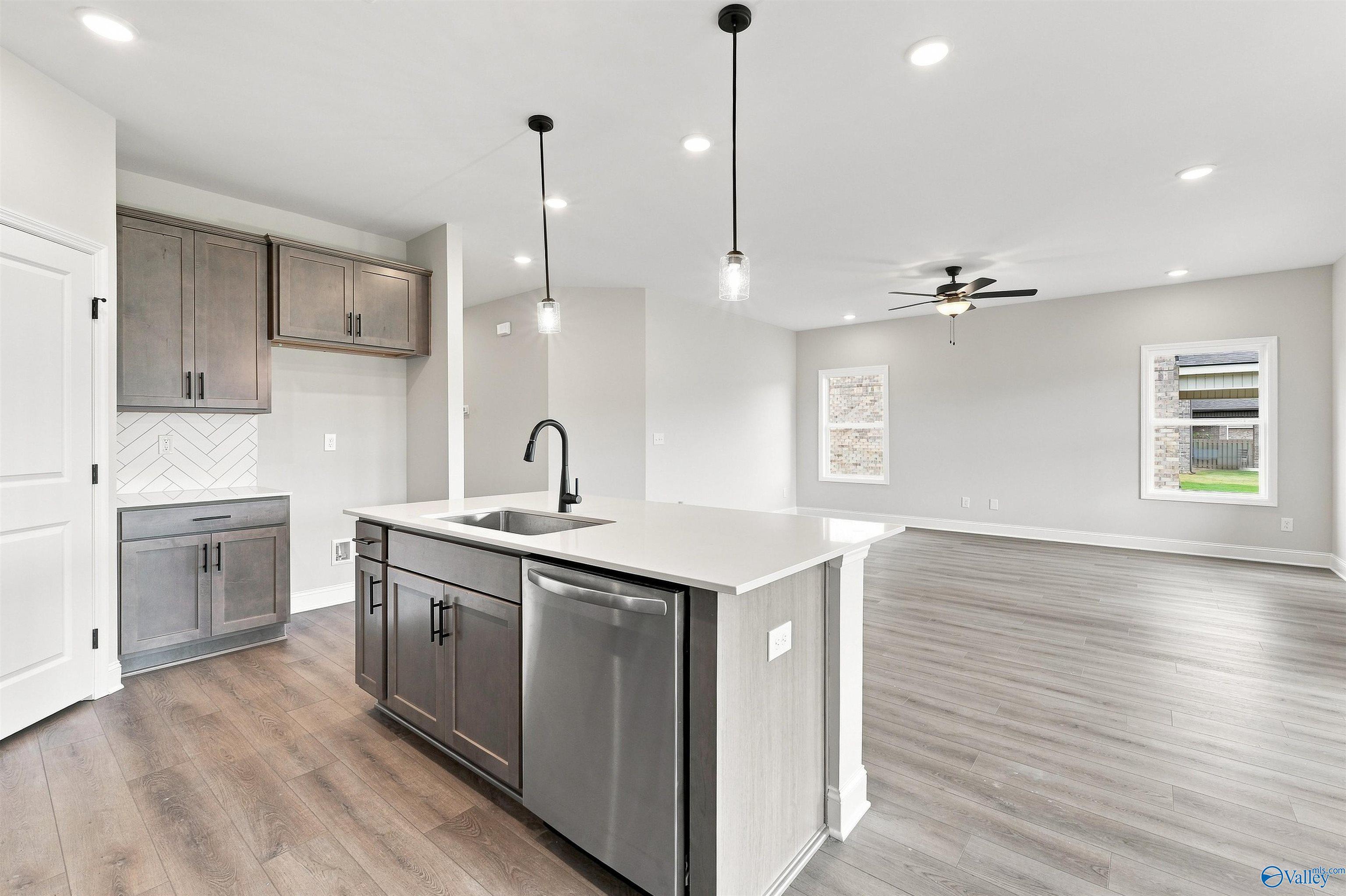 Open-concept kitchen with island, gray cabinets, and luxury vinyl plank flooring in Davidson Homes Franklin C, Athens, Alabama