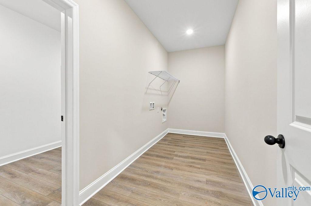 Laundry room with wire drying rack, luxury vinyl plank flooring, and neutral walls in Davidson Homes' The Rockford plan, Cain Park, Hartselle