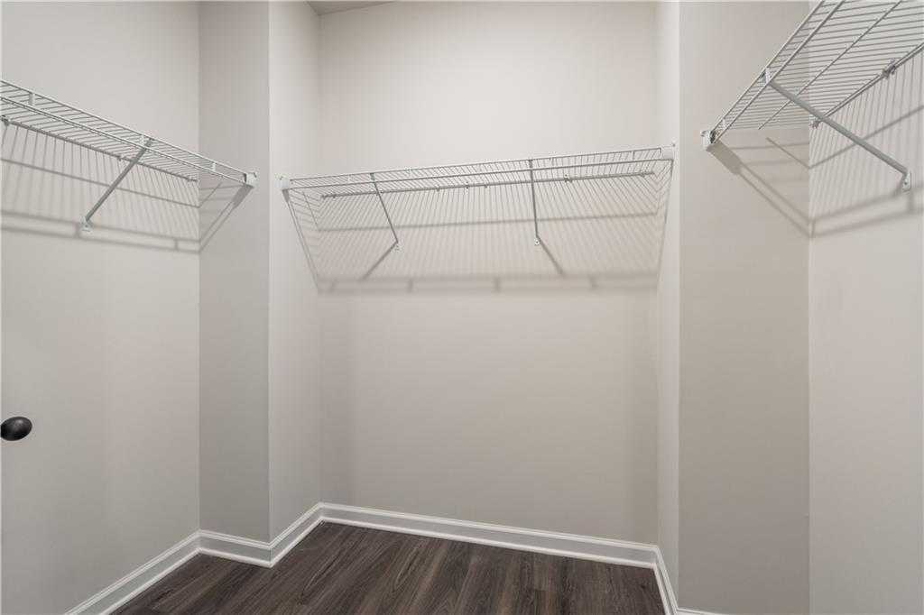 Spacious walk-in closet with adjustable wire shelving, neutral walls, and hardwood floors in Davidson Homes The Daphne B, Loganville, GA