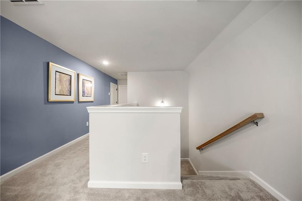 Upstairs hallway featuring blue accent wall, wooden staircase railing, framed artwork in Davidson Homes The Willow B, Riverwood, Dallas, GA
