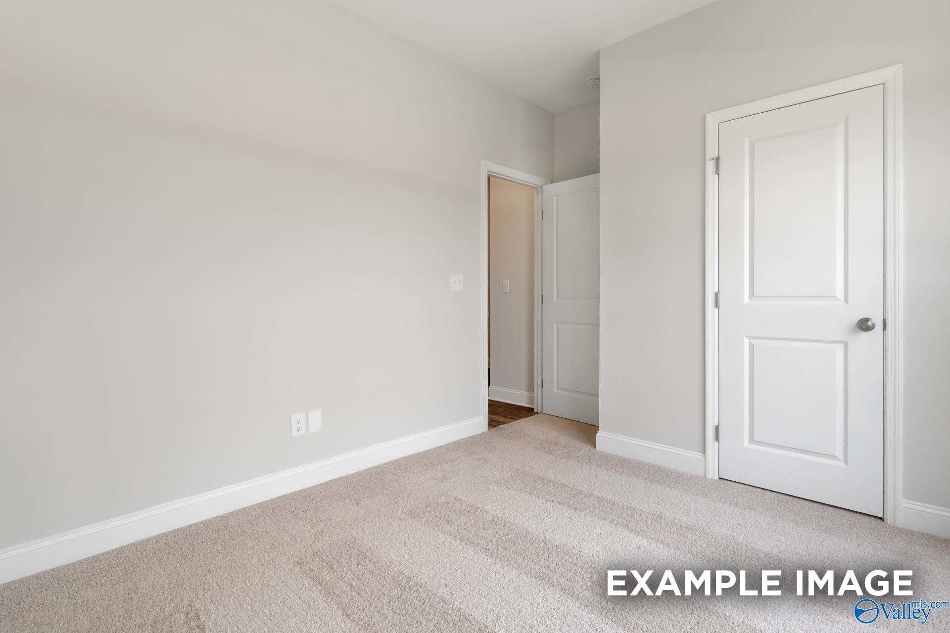 Bright secondary bedroom with neutral beige walls, carpeted floor, and white doors in Davidson Homes The Asheville C, Meridianville, Alabama