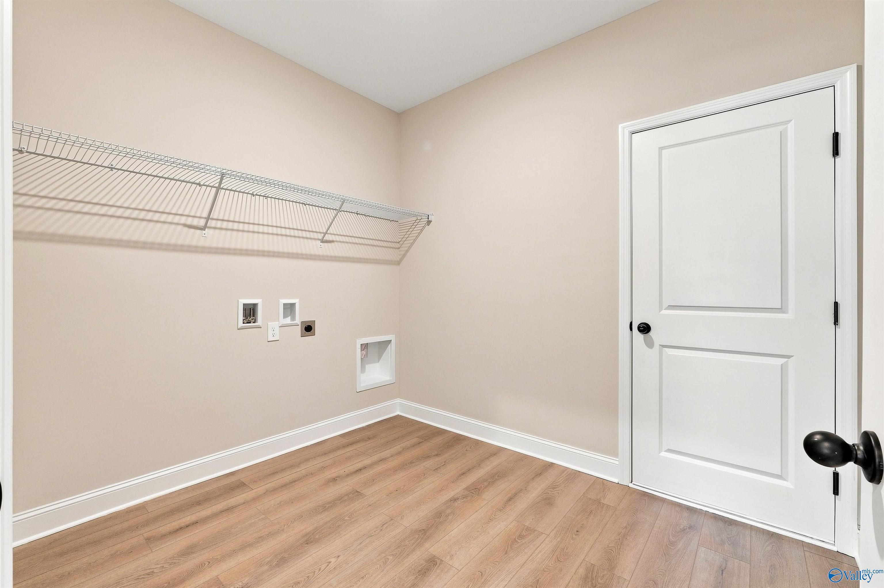 Laundry room with wire shelving and wood-look flooring in The Oxford floor plan at Kendall Farms, Toney, Alabama.