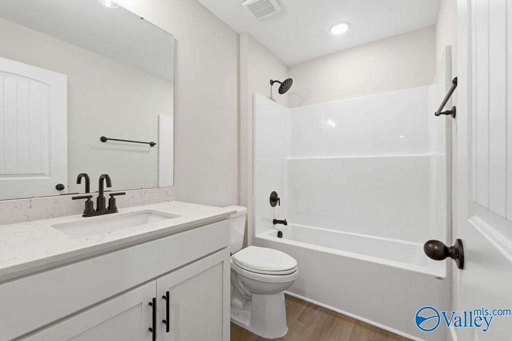 Modern master bath with white quartz vanity, soaking tub, and glass shower in Davidson Homes The Rockford, Hartselle, Alabama