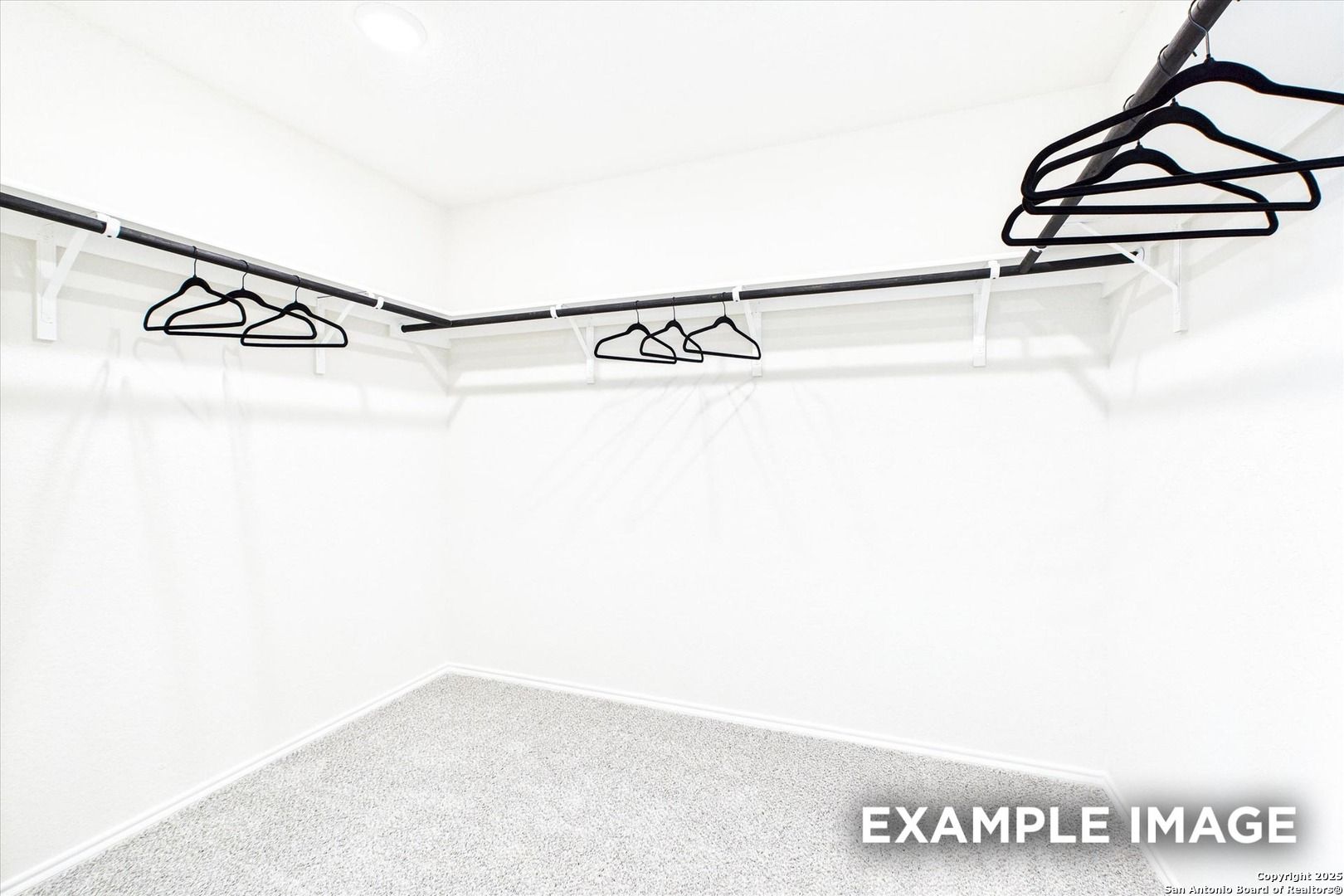 Spacious walk-in closet with black hangers on corner rods in white room, The Florence C by Davidson Homes, San Antonio