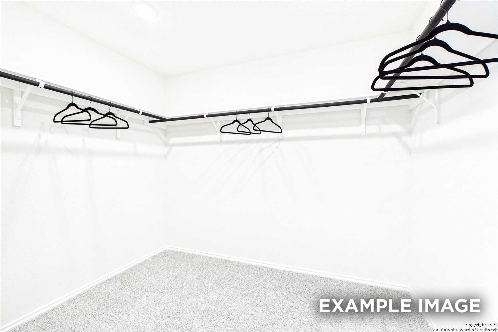 Spacious walk-in closet with black hangers on corner rods in white room, The Florence C by Davidson Homes, San Antonio