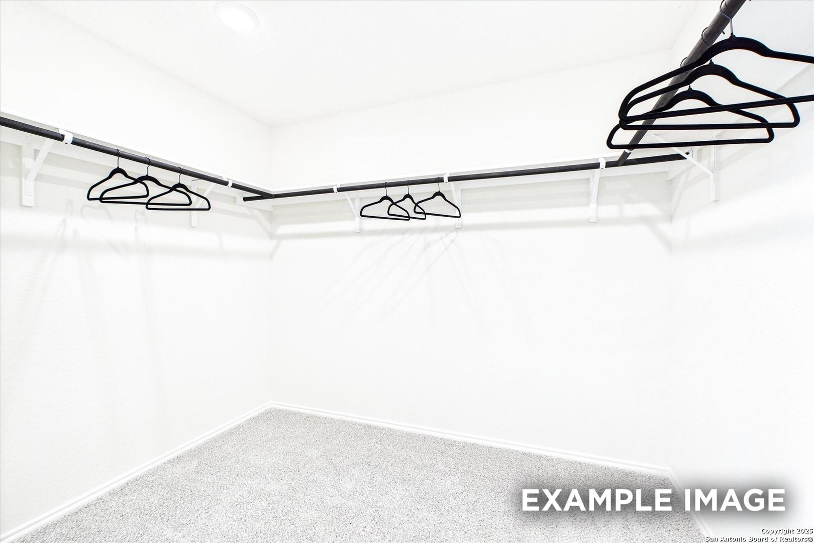 Spacious walk-in closet with black hangers on corner rods in white room, The Florence C by Davidson Homes, San Antonio