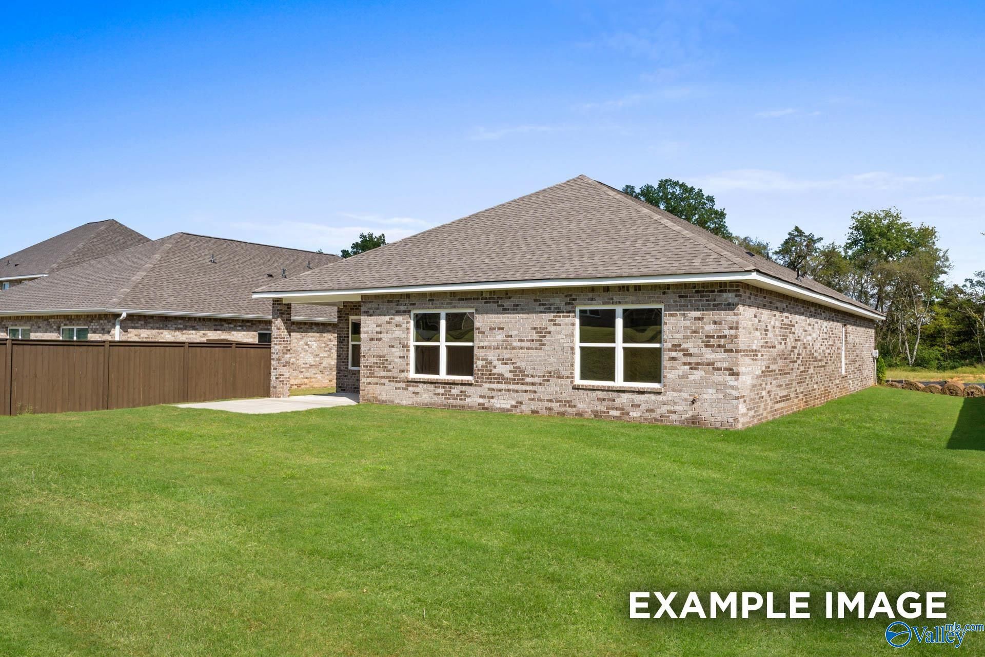 Modern brick single-story home with gabled roof, attached garage, and lush green yard in Walker's Hill, Meridianville, Alabama