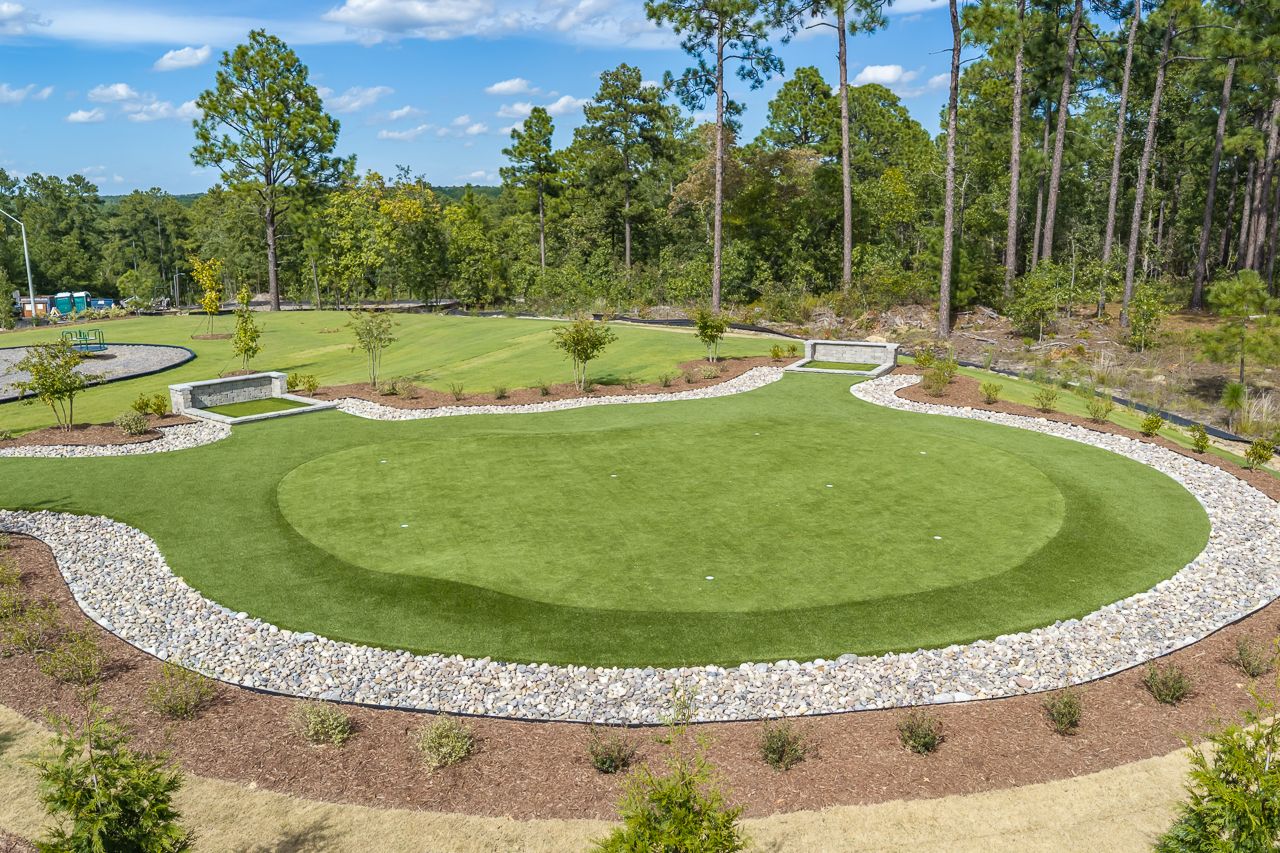 Community putting green at Montrose in Aberdeen, North Carolina by Davidson Homes with stone border and pine trees