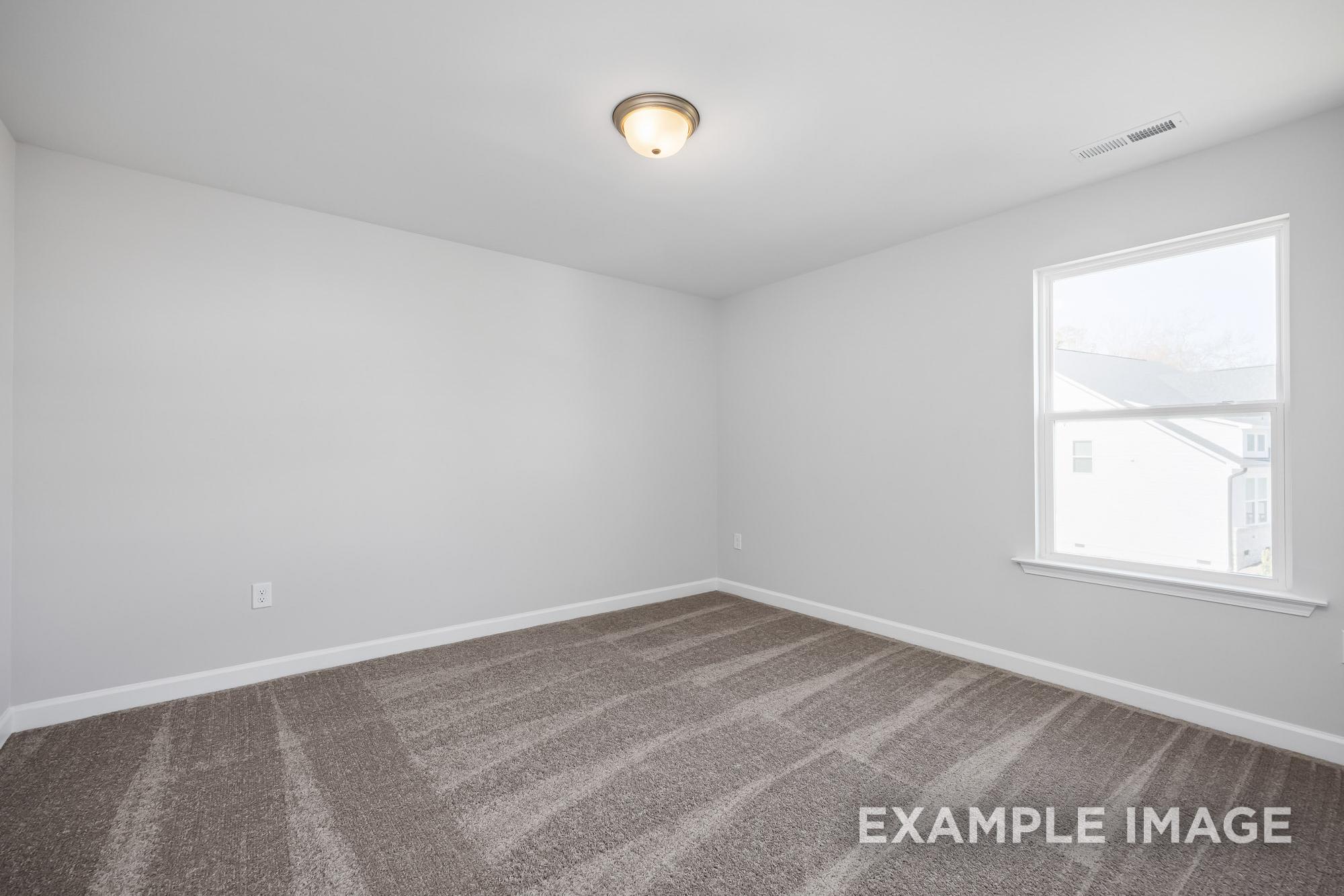 Spacious empty bedroom in The Cypress B II home with neutral carpet, white walls, large window, and ceiling light