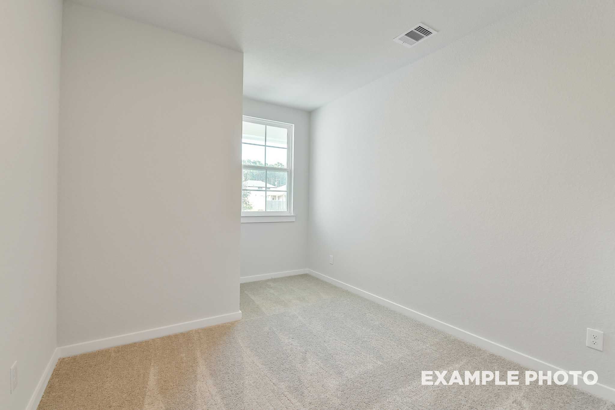 Bright empty bedroom with beige carpet and white walls in The Colorado by Davidson Homes, Beasley, Texas new construction home