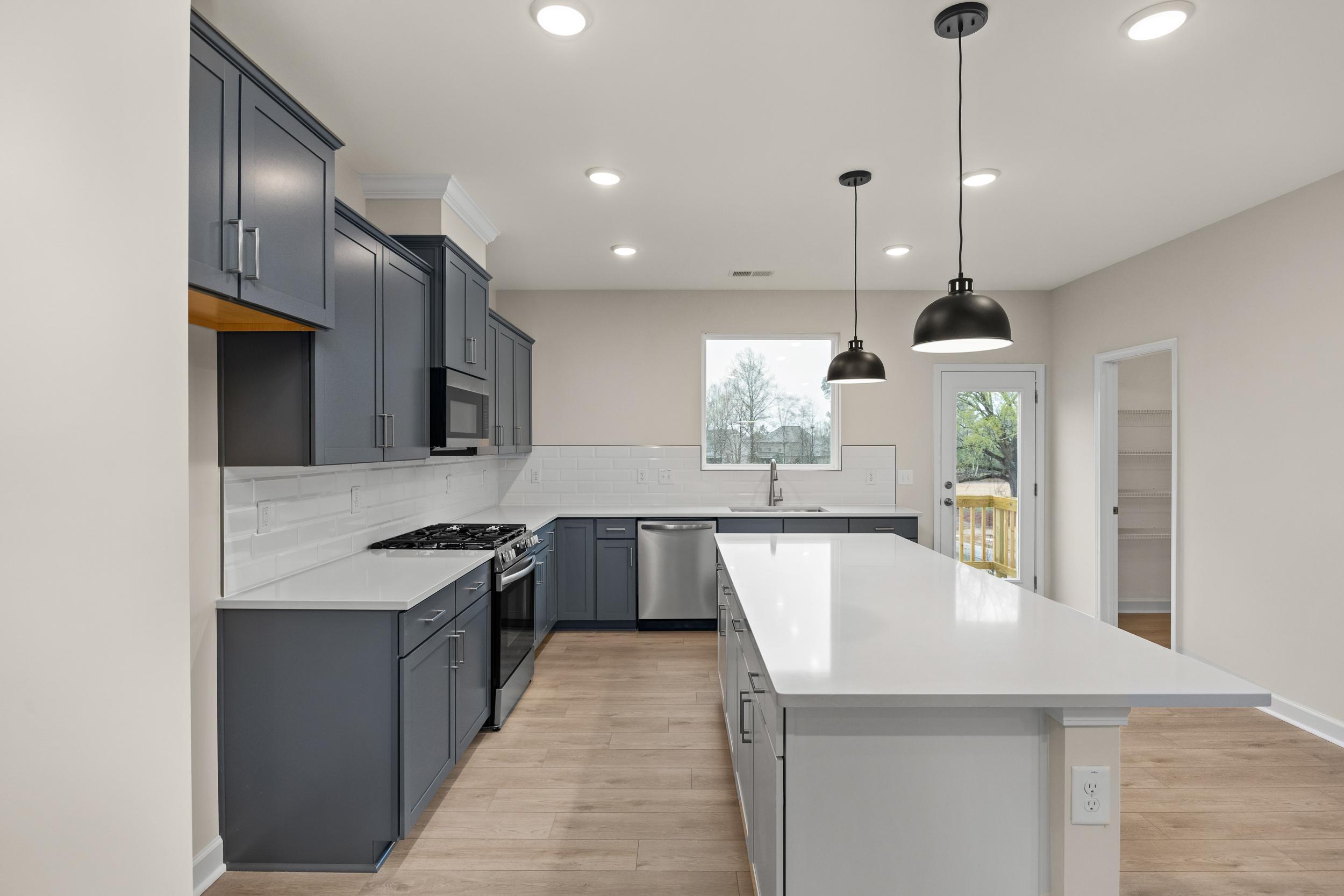 Contemporary kitchen with navy cabinets, white quartz island, stainless appliances at Forestville Yard Townhomes in Knightdale NC