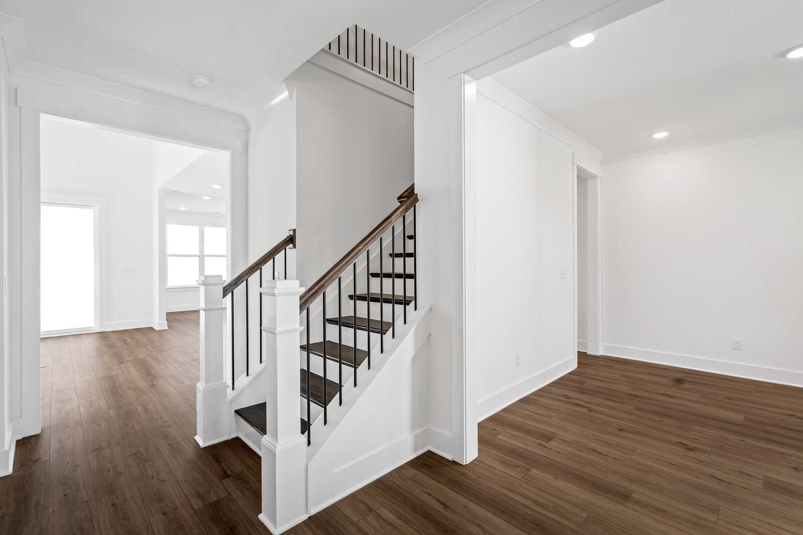 Elegant wooden staircase with iron balusters in open foyer, hardwood floors, The Hawkins 4-bedroom home by Davidson Homes, Murfreesboro, TN