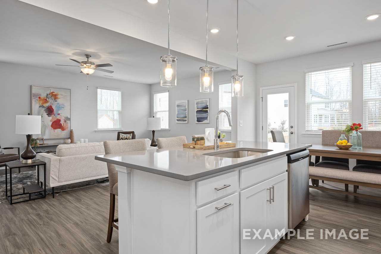 Open-concept kitchen and living room in The Grace A home with white island, pendant lights, and hardwood floors