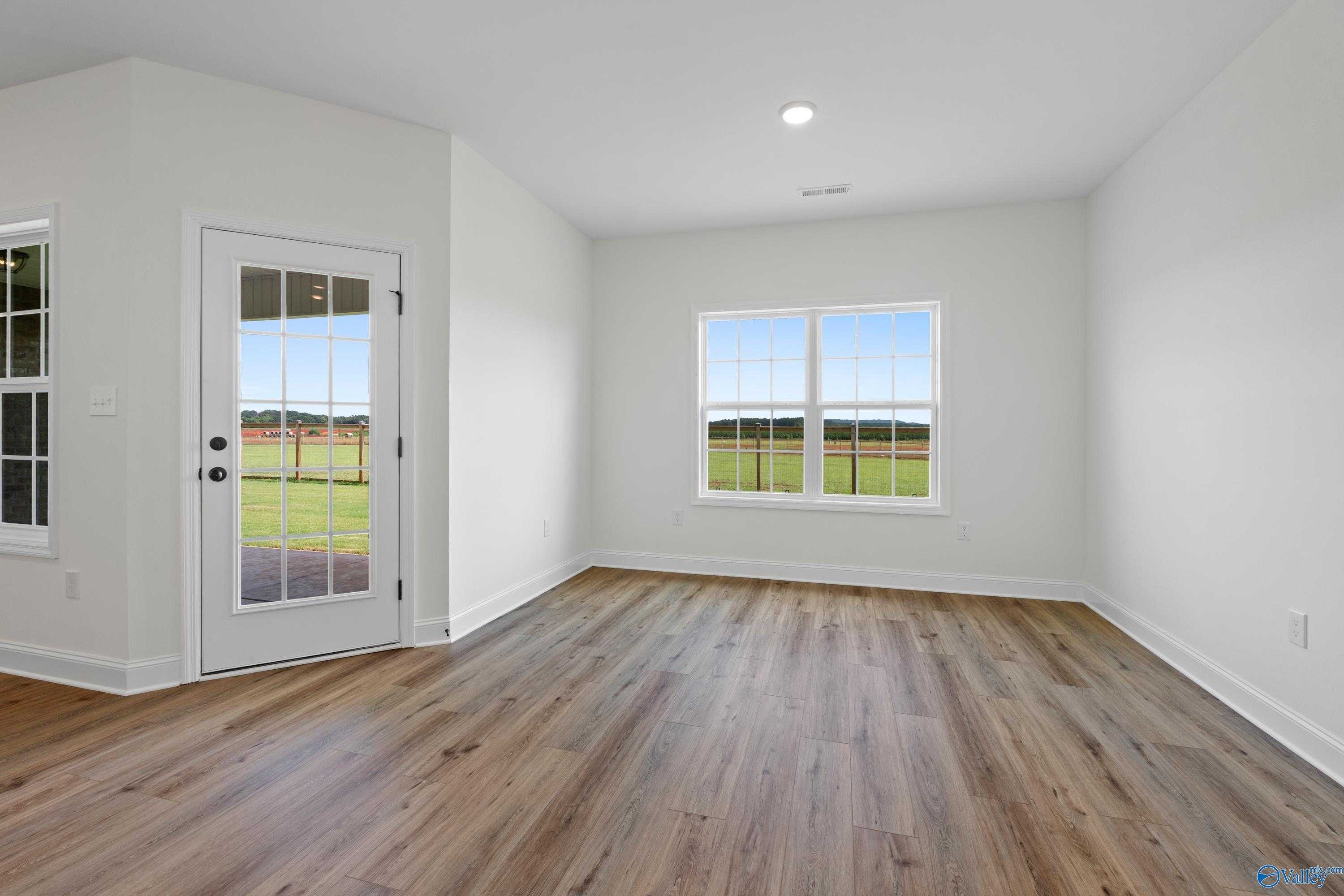 Bright home office with hardwood floors, French doors, and large windows showcasing green pastures in The Rockford B, Toney, Alabama