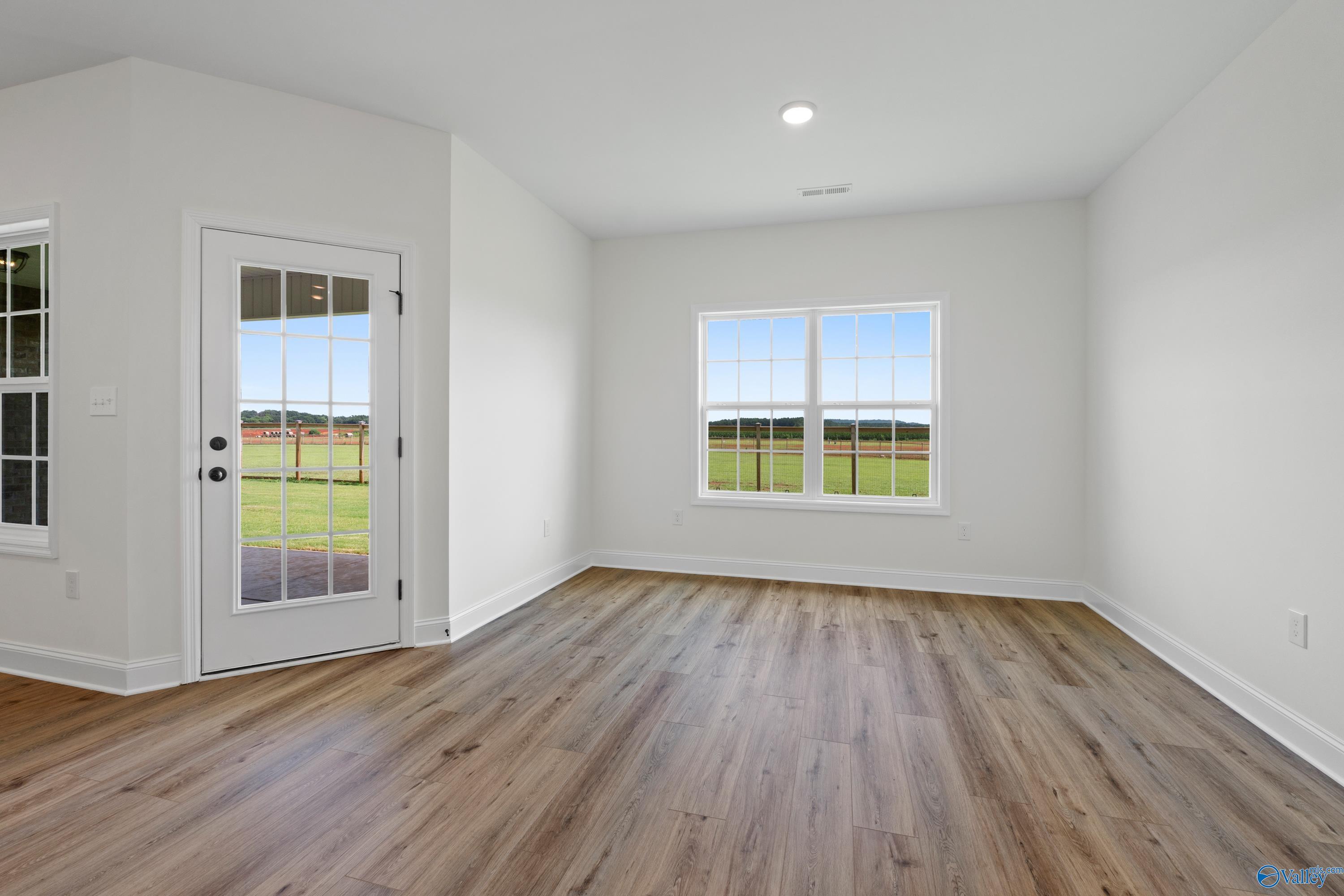 Bright sunroom with hardwood floors, white walls, French doors to green pasture and barn in The Rockford B, Toney, Alabama