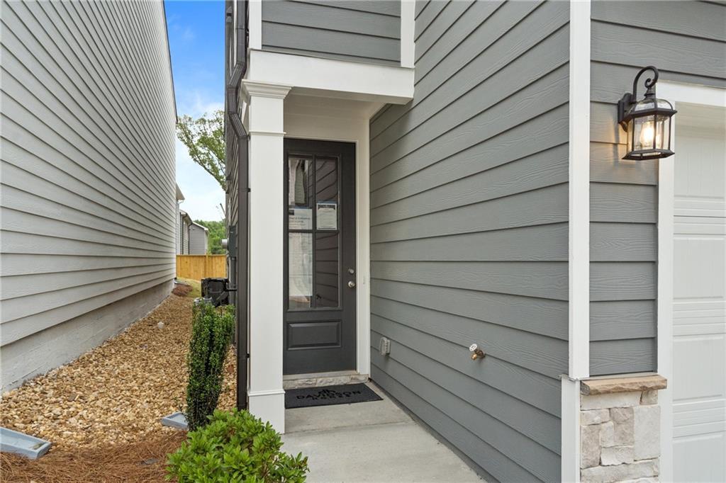 Modern gray two-story home exterior with black glass-front door, white columns, lantern light, and 2-car garage in Kennesaw, Georgia