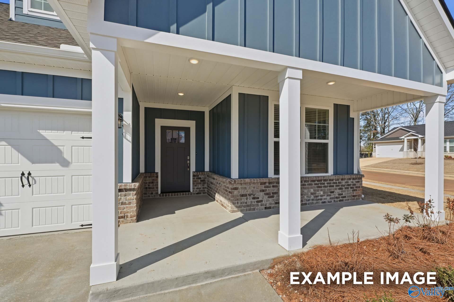 Modern blue board-and-batten home with covered porch, white columns, 2-car garage, brick accents in Evergreen Mill, Madison, Alabama