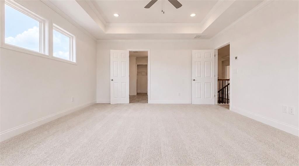 Spacious bedroom with tray ceiling and walk-in closet in The Hickory C floor plan at Wehunt Meadows, Hoschton, Georgia.